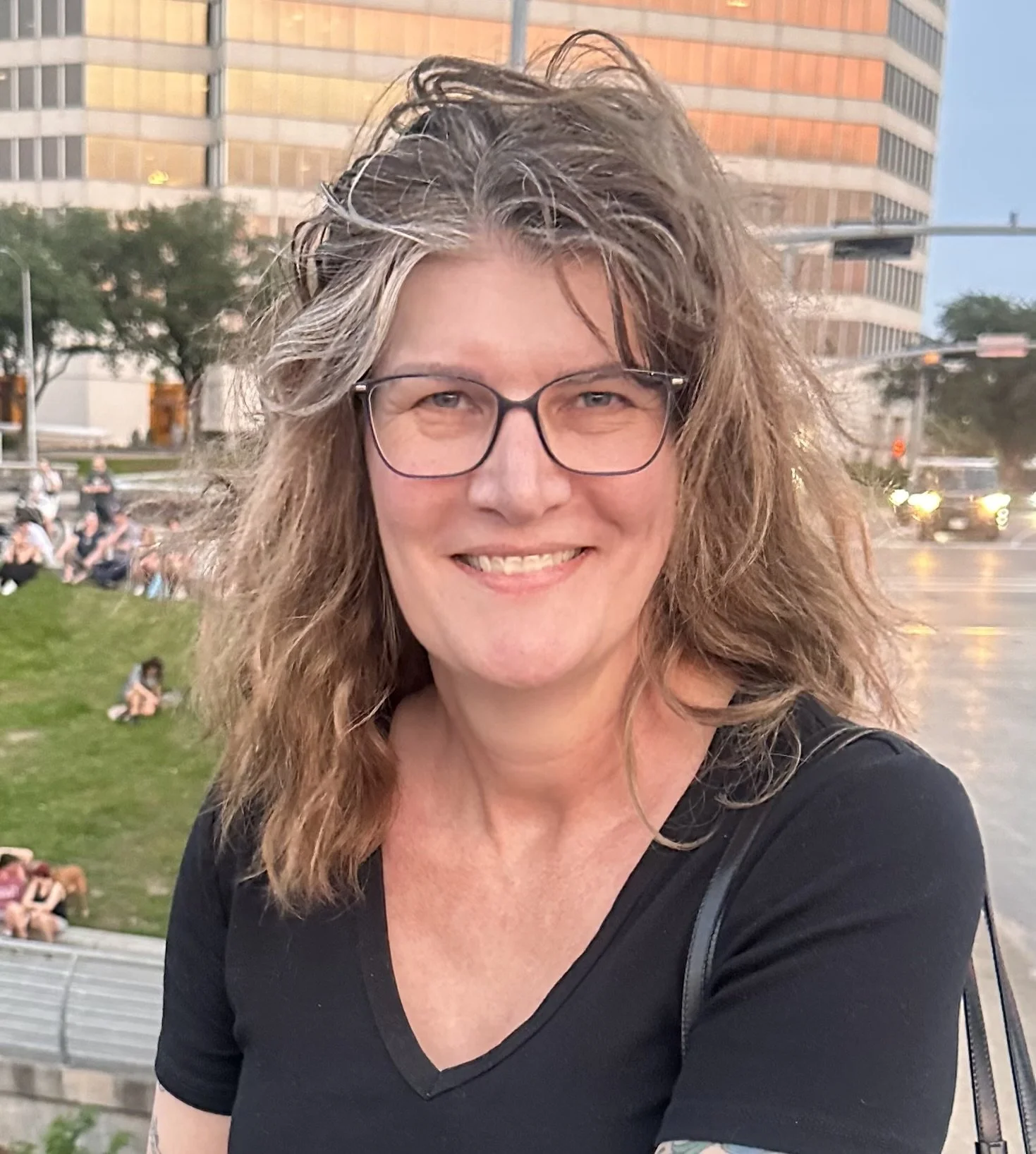 white woman with wavy light brown hair wearing glasses