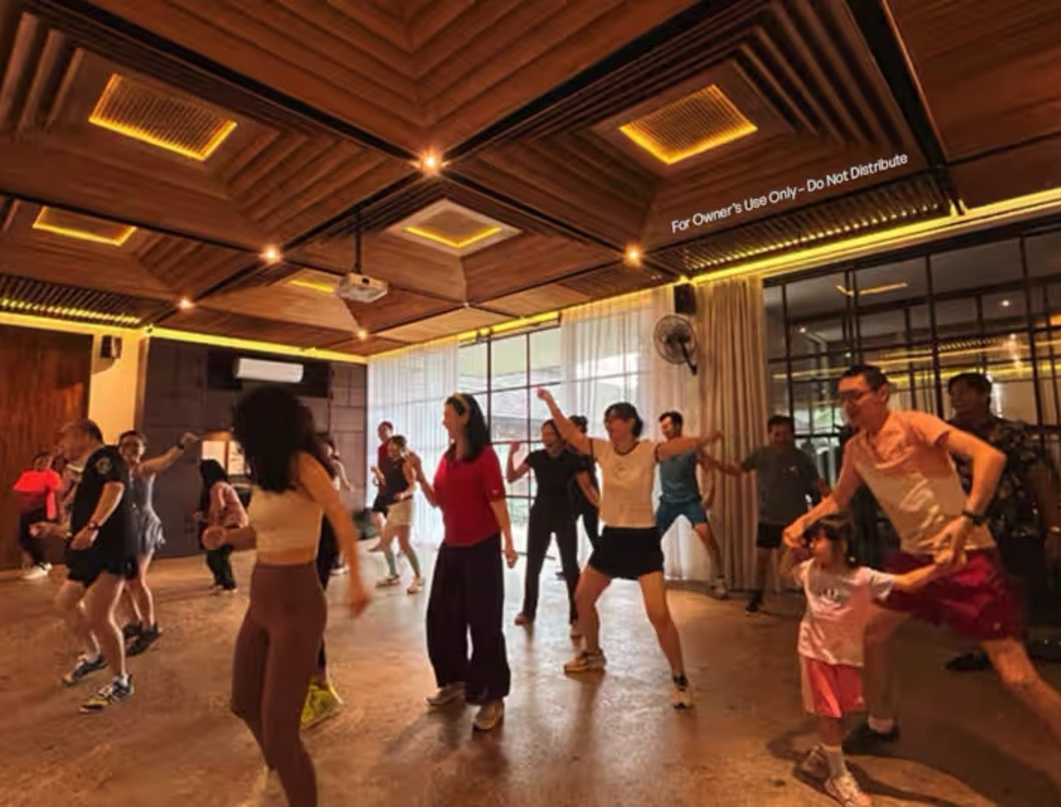 Group of people dancing in a room with wooden ceiling and large windows.