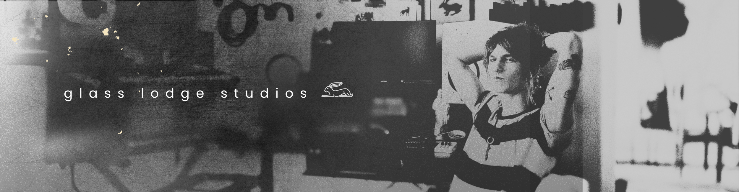 Black and white photo of a woman sitting at a desk in a studio, with the text 'glass lodge studios' and a small rabbit logo overlayed.