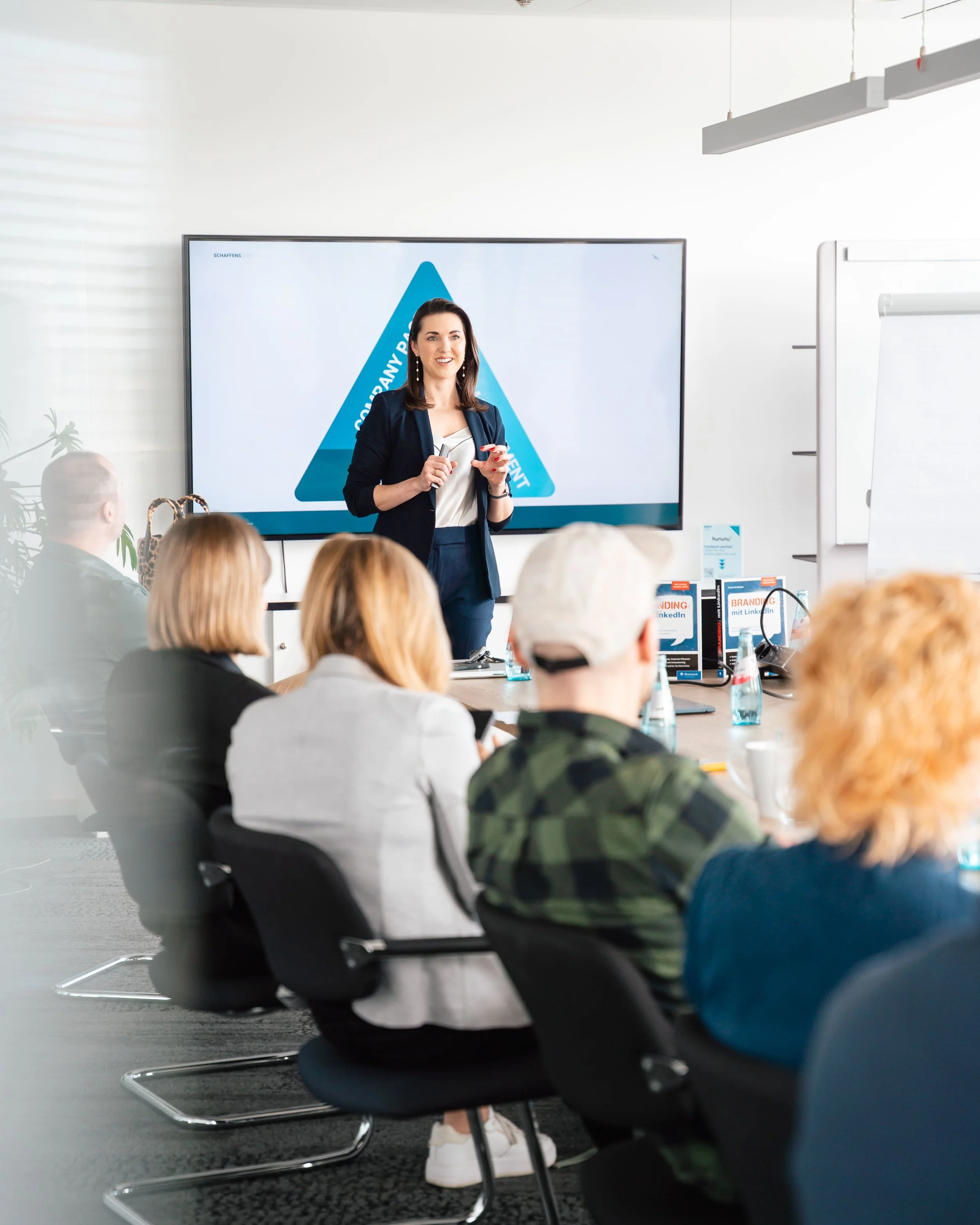 frau im business anzug steht vor monitor vor einem publikum