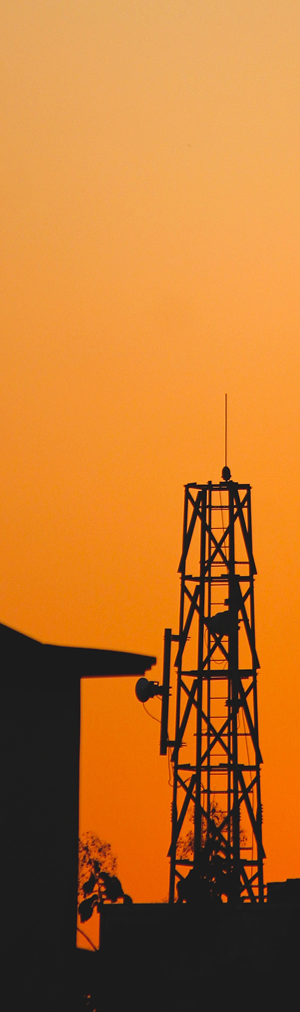 Secteur Telecom : Silhouette d'une tour de communication contre un ciel orange au coucher du soleil.