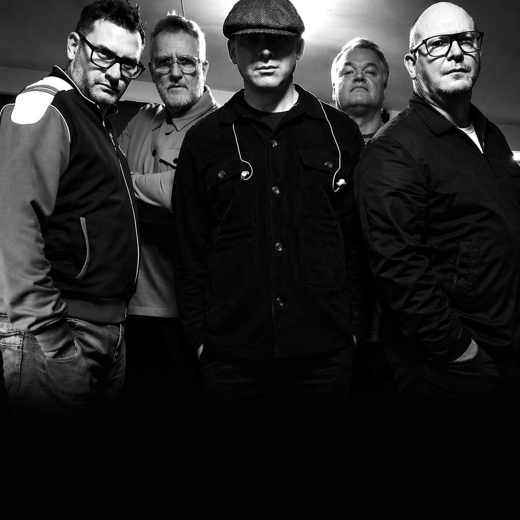 Black and white photo of five men standing in a group, with serious expressions, in an indoor setting.
