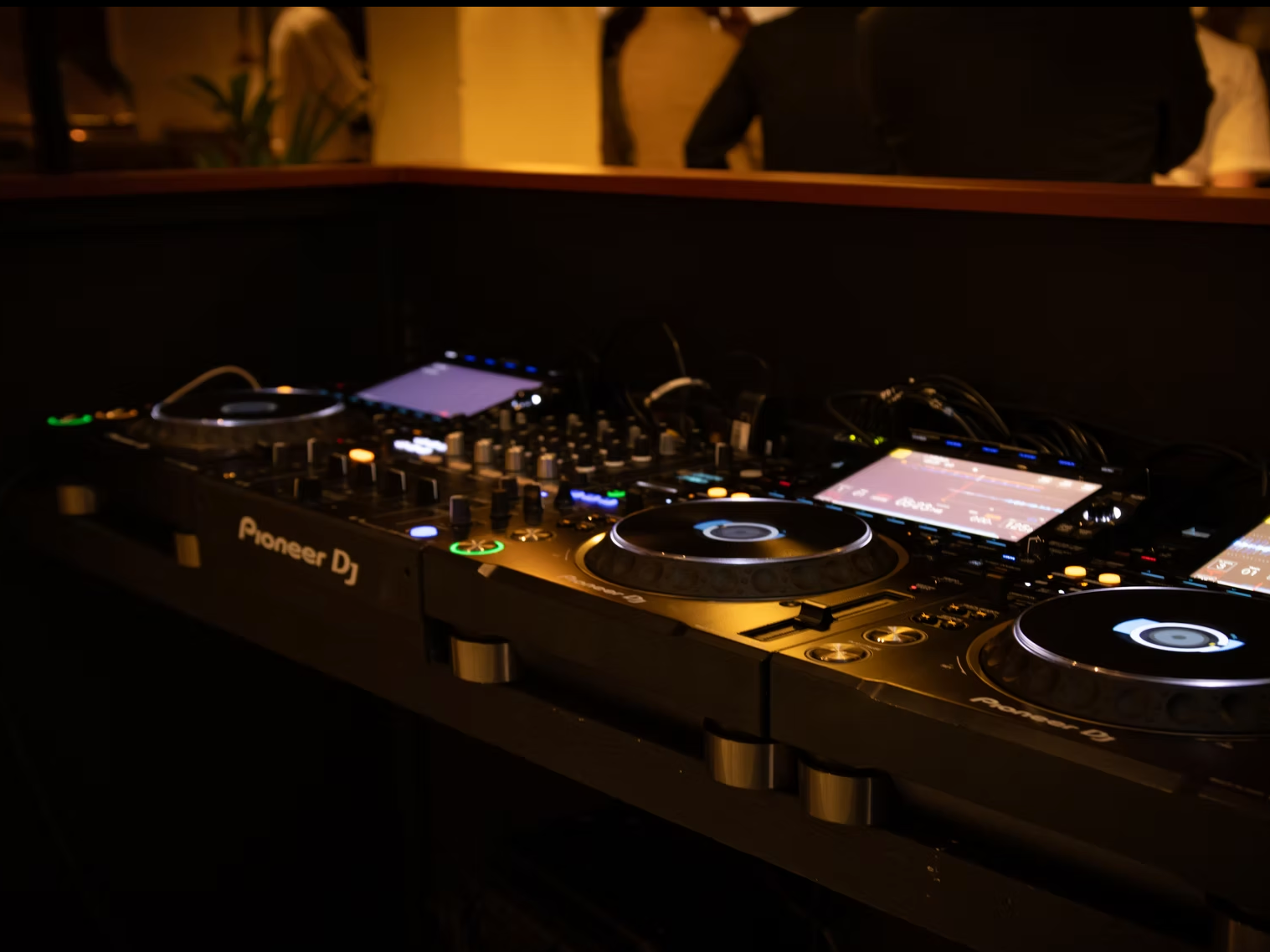 DJ mixer and turntables at a dimly lit nightclub or party venue.