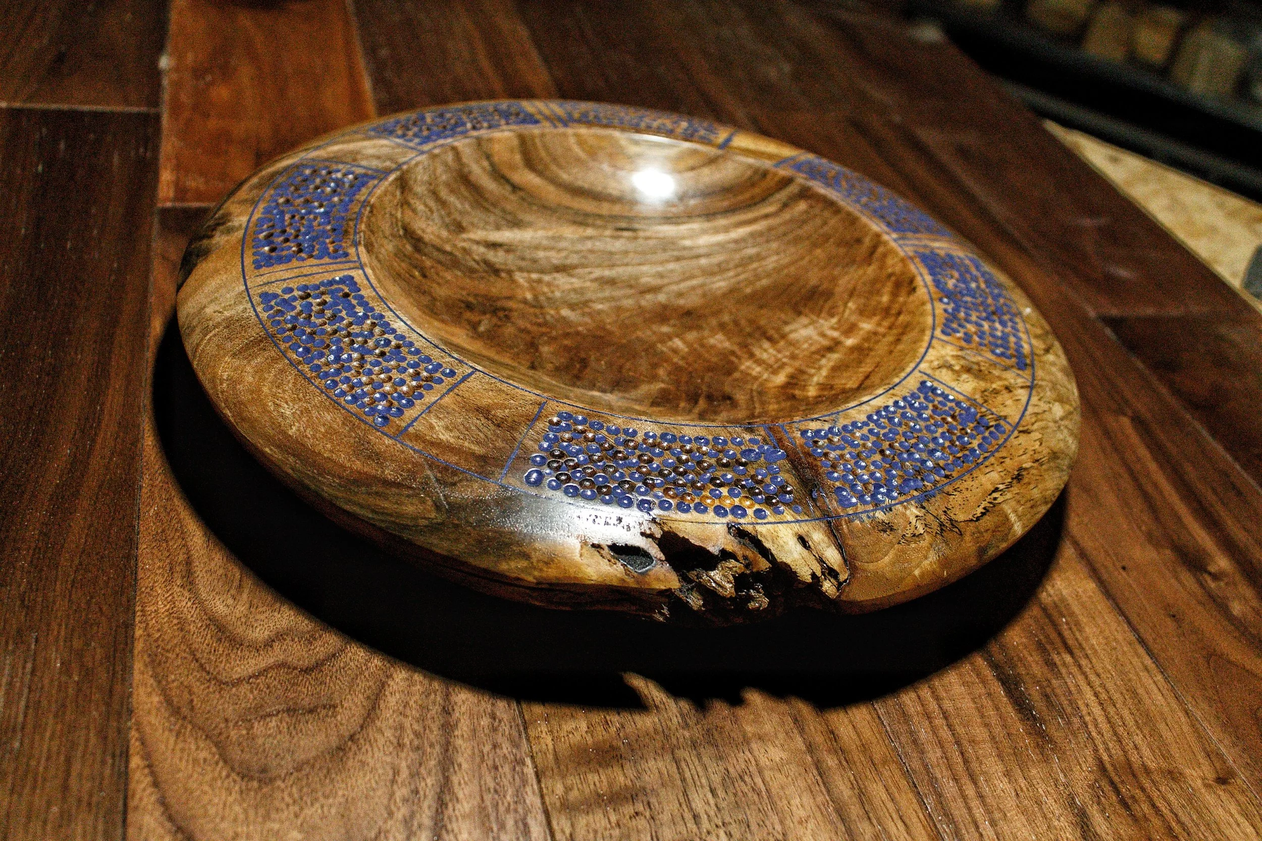 Wooden bowl with blue bead inlay on wooden surface