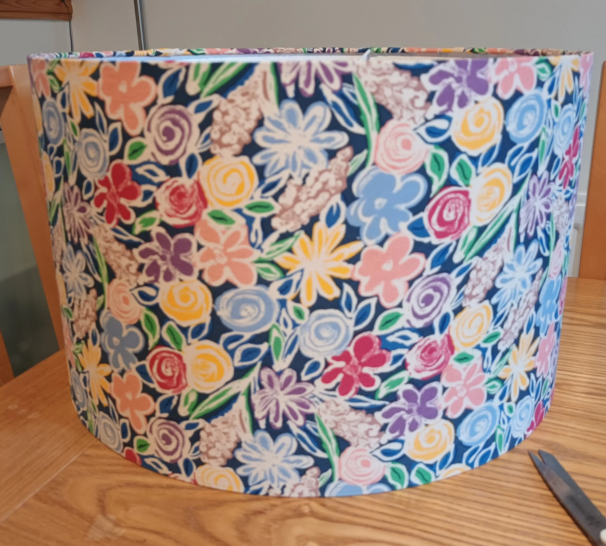 Floral patterned lampshade on wooden table.