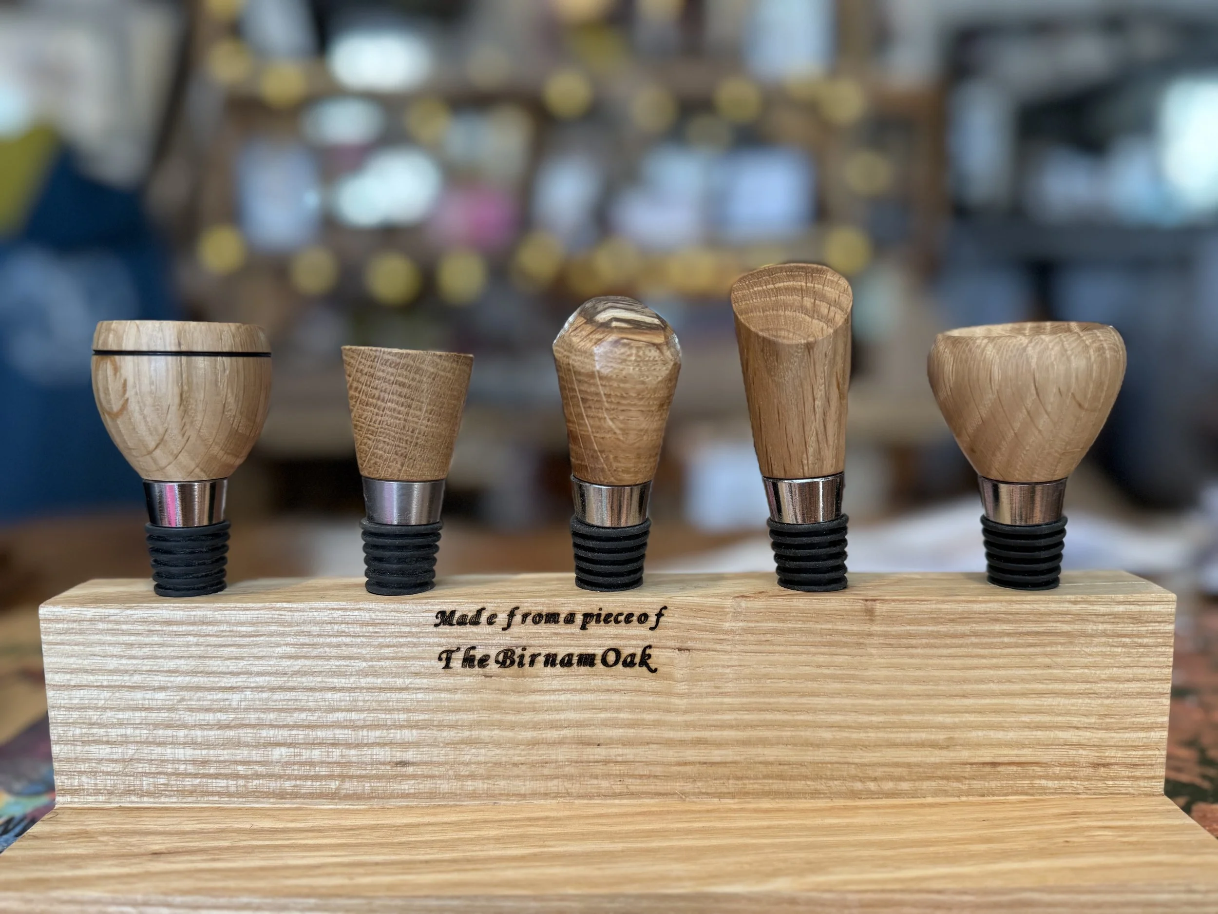 Set of five wooden furniture legs with black rubber pads, mounted on a wooden base with the inscription 'Made from a piece of The Birnam Oak' in a workshop.