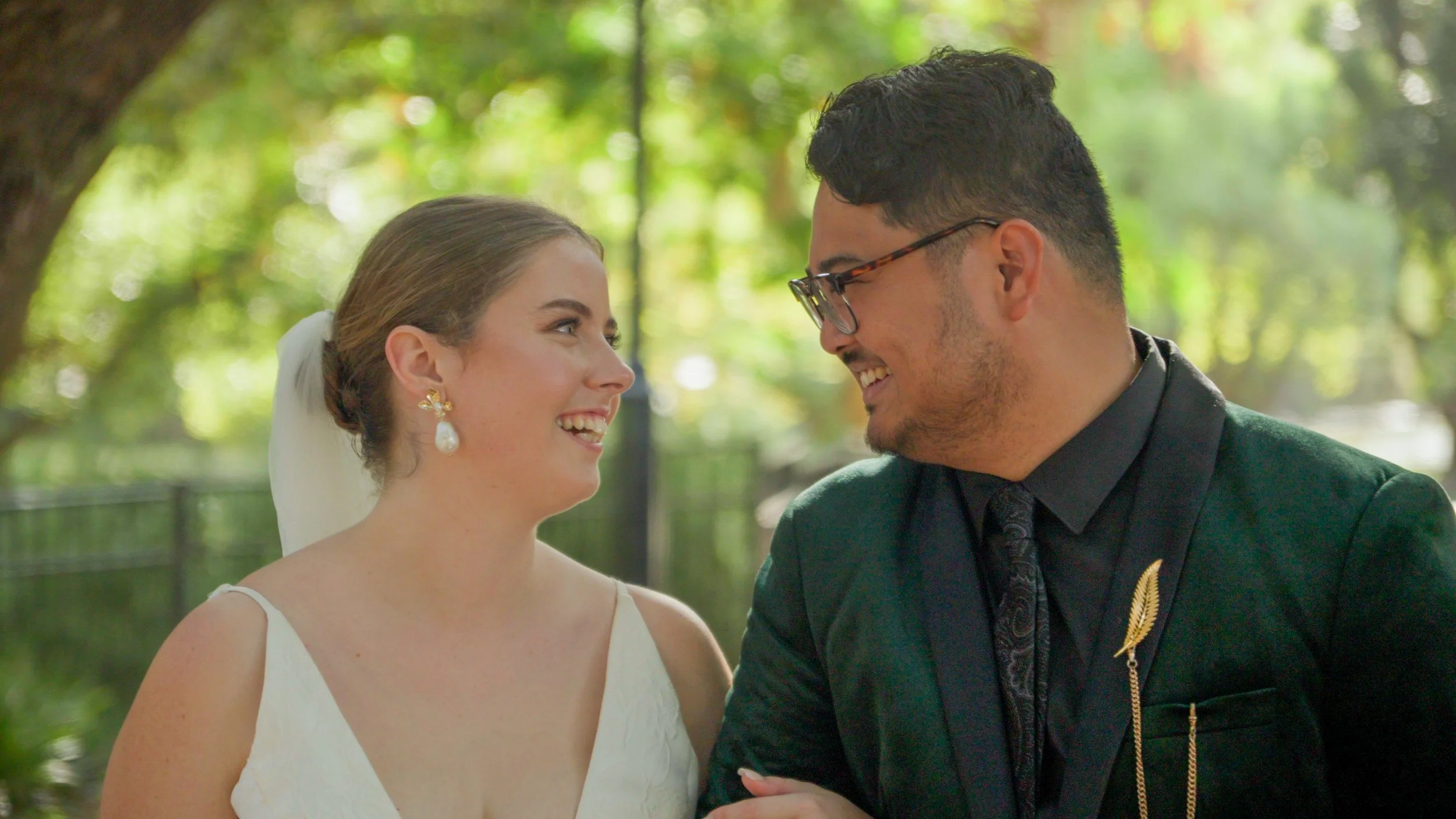 Bride and groom smiling at each other outdoors