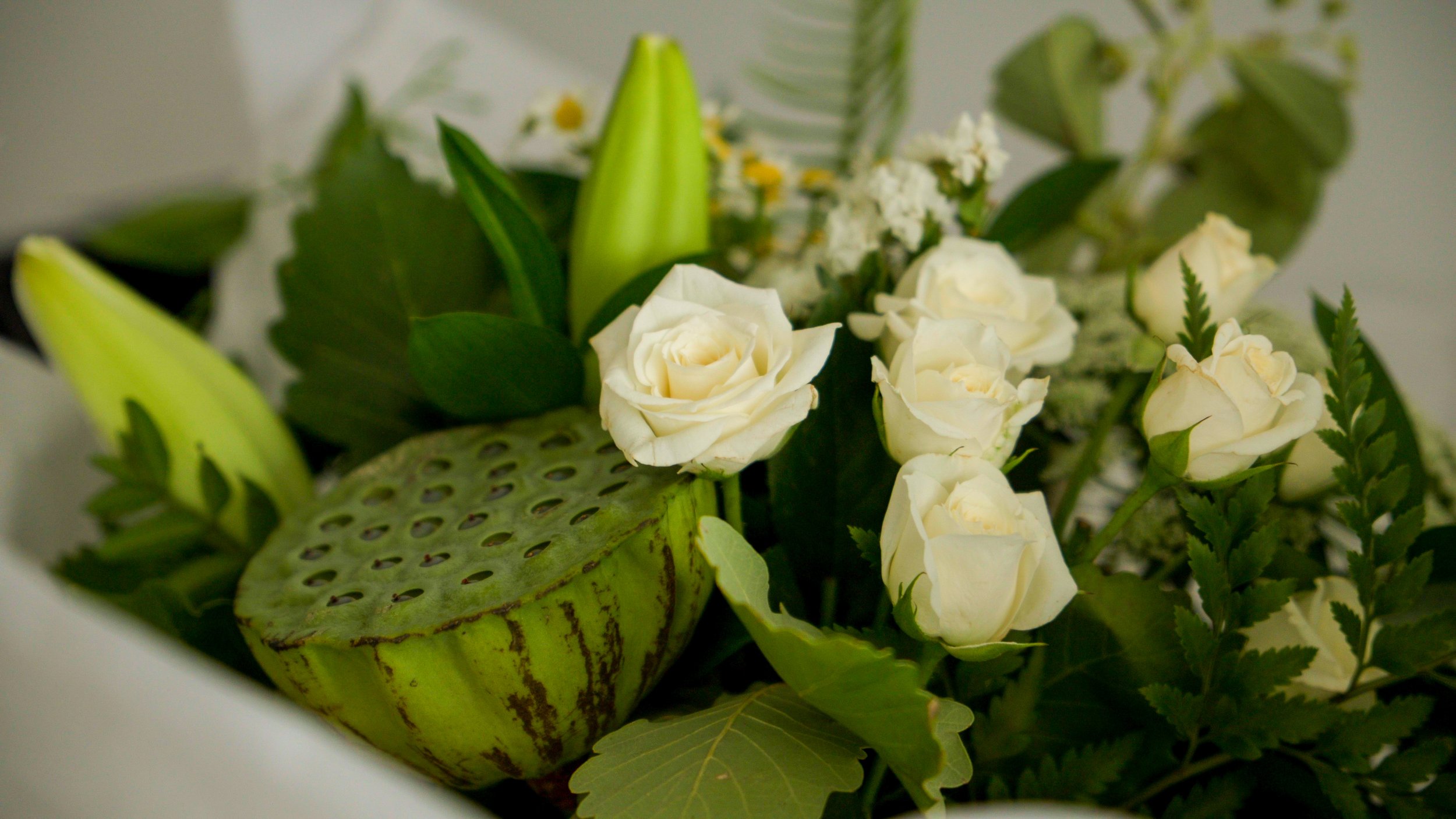 Bouquet with white roses, lotus seed pod, and green foliage