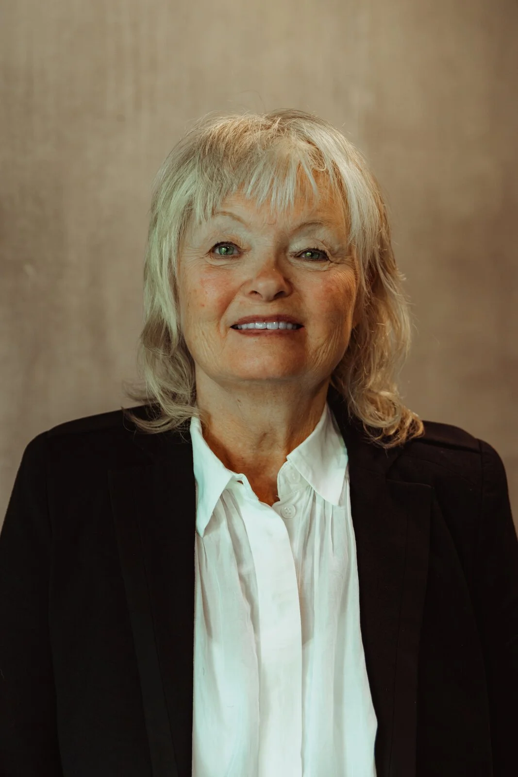 Jo, Betwixt dancer, smiling in a black blazer with shoulder-length blonde-grey hair.
