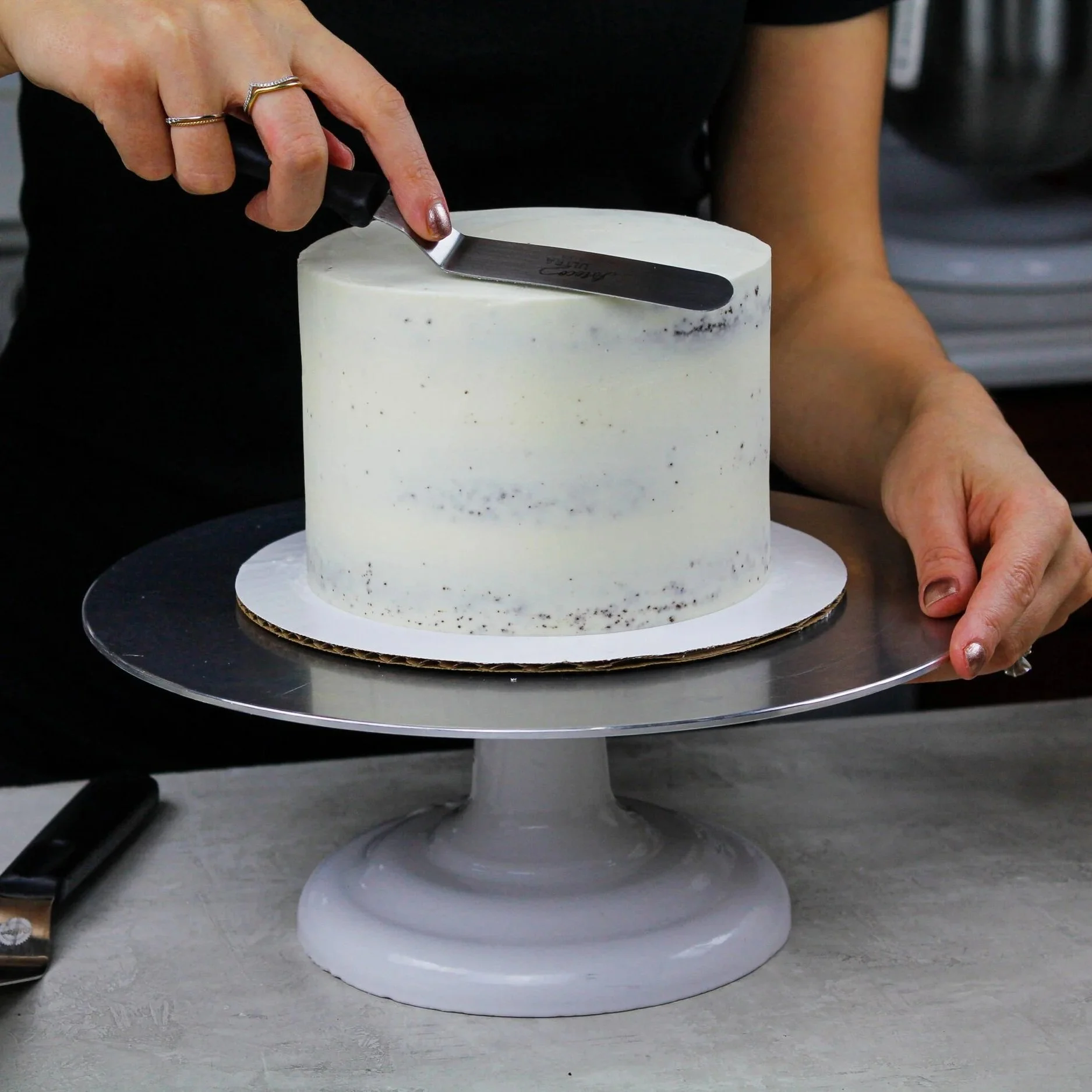 cleaning-up-top-edge-with-small-offset-spatula-after-adding-crumb-coat-of-frosting-edited-scaled.jpg