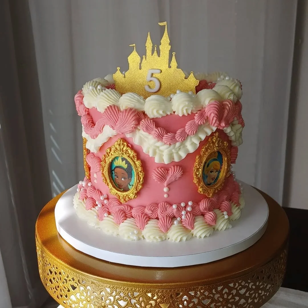 Princess 👑 💖

This cake is a dream come true for a little princess! 

With detailed vintage style piping, white pearl sprinkles,  3D printed gold castle topper, gold sparkles, and edible image portraits of her favorite princess with chocolate frame
