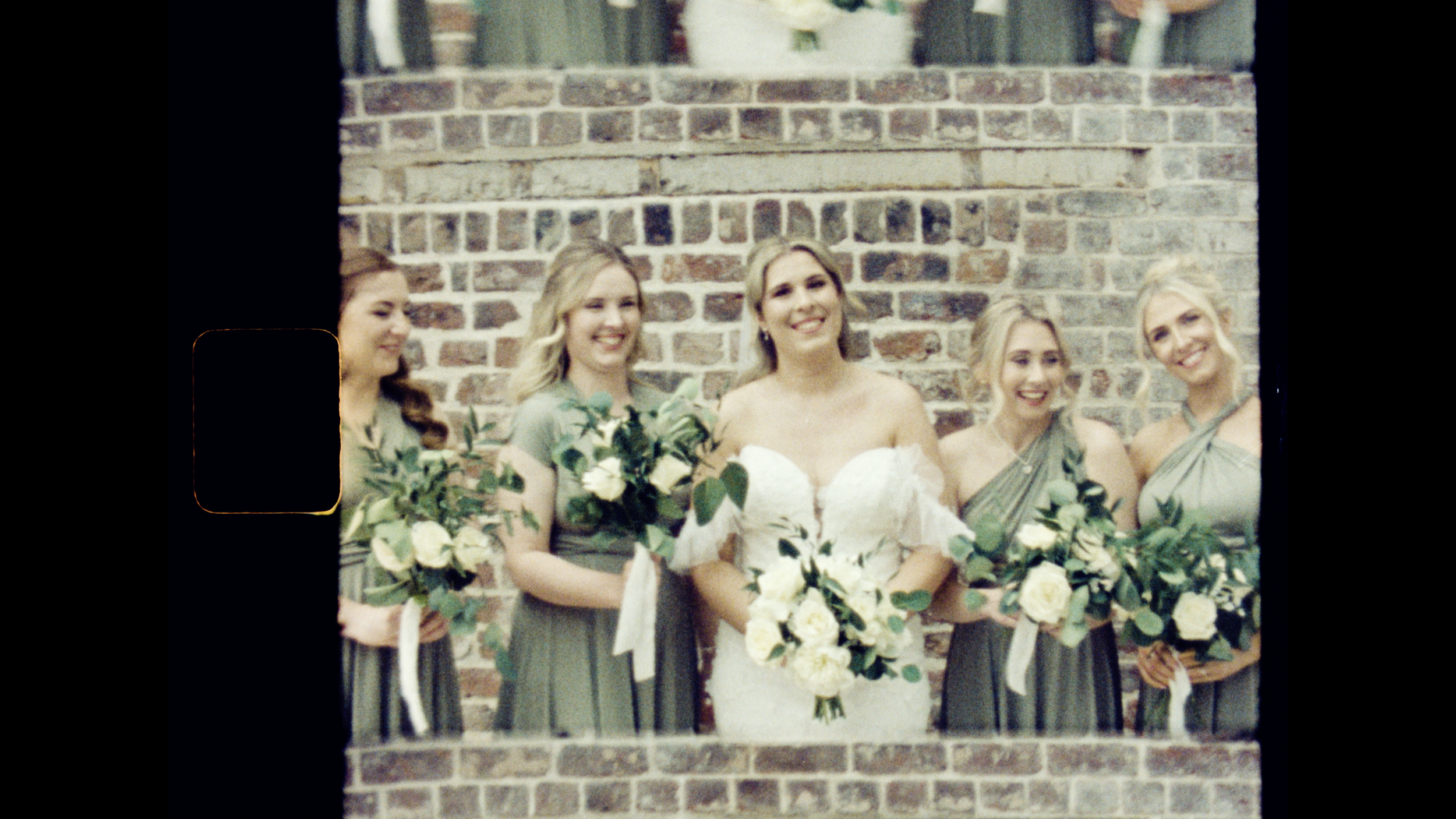 Bride and bridesmaids smiling with bouquets, wearing peach and blush dresses outdoors, with greenery in the background.