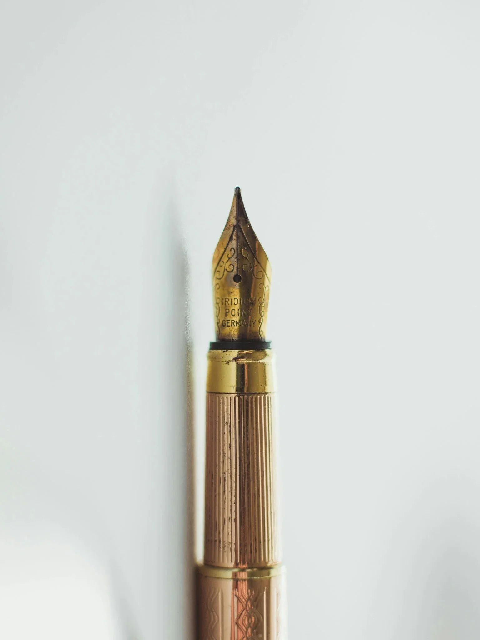 Close-up of a gold fountain pen nib with the words "TRIDUUM POINT GERMANY" engraved on it, set against a plain white background.