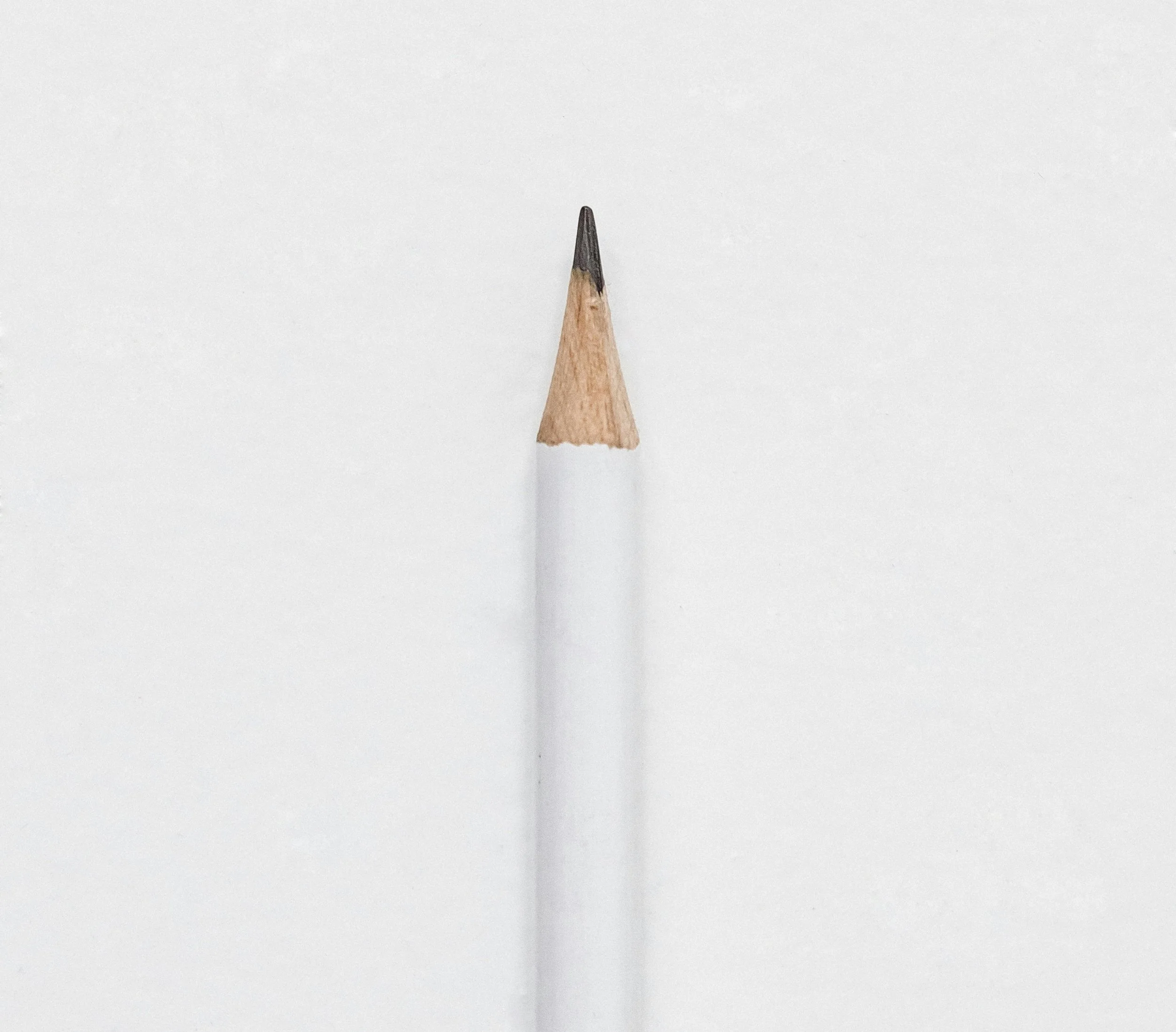 Close-up photograph of a sharpened wooden pencil tip against a plain white background.