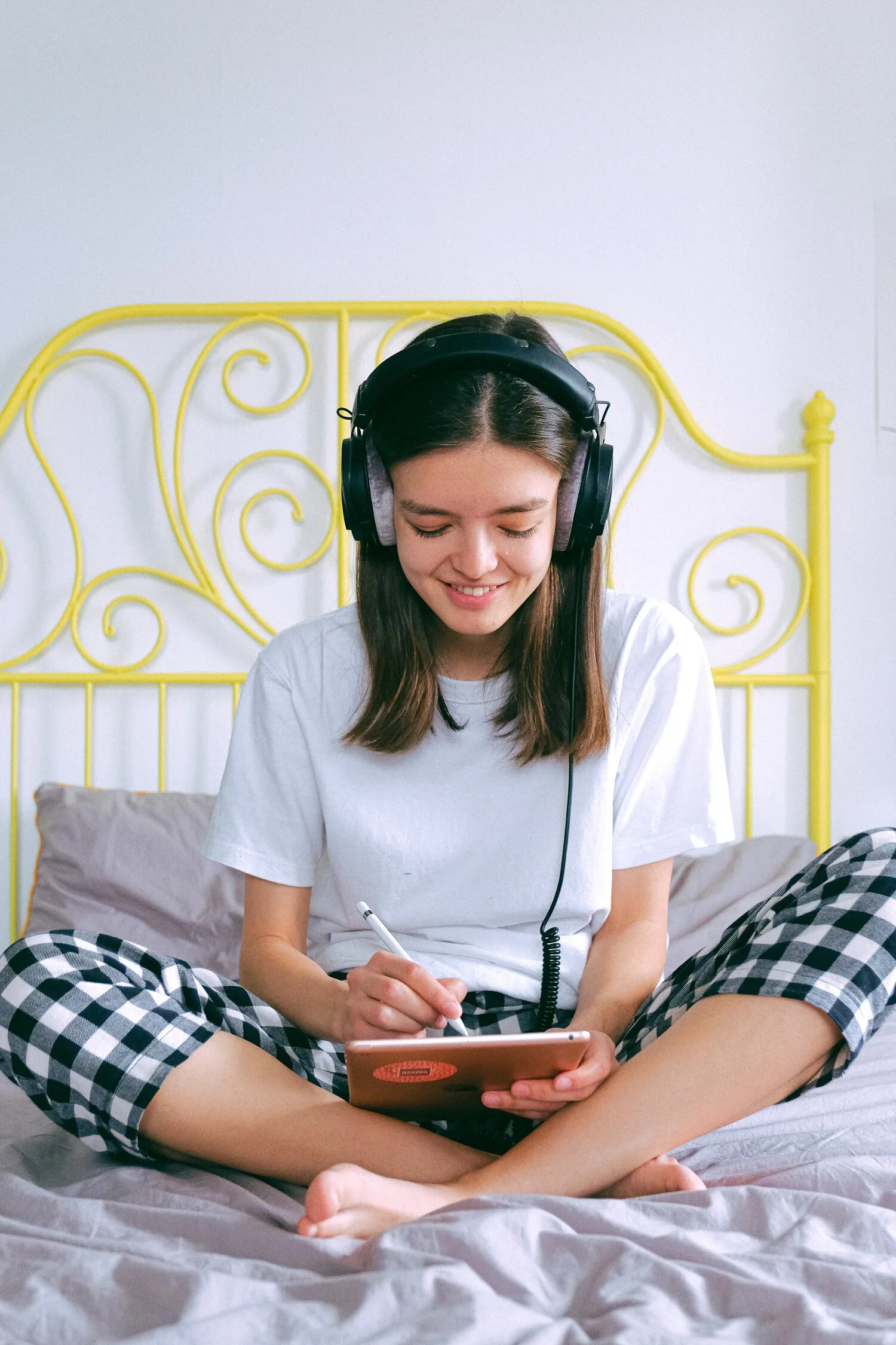 girl sitting on bed with headphones on