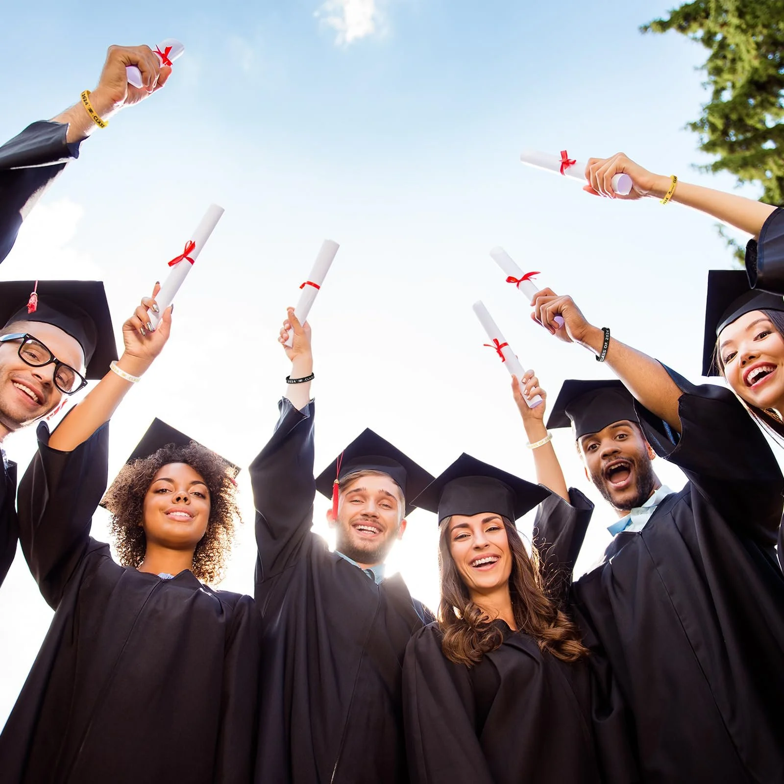 graduates holding up their dipolmas