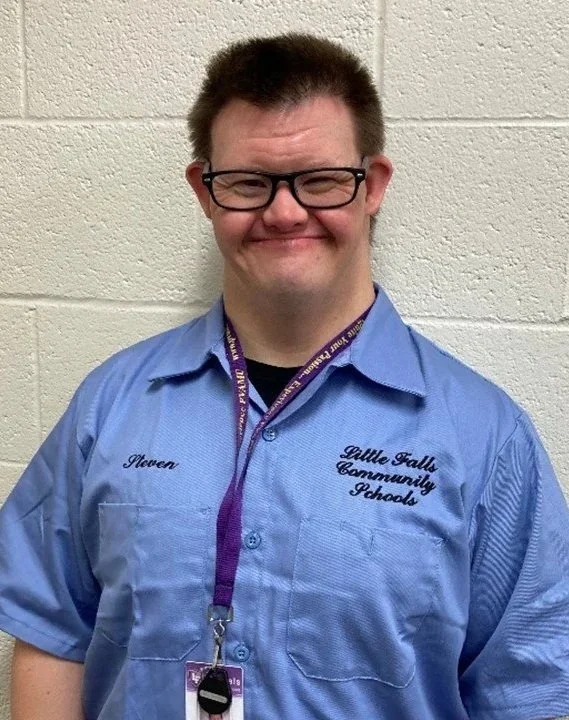 Steven is a white man wearing glasses and a work uniform.