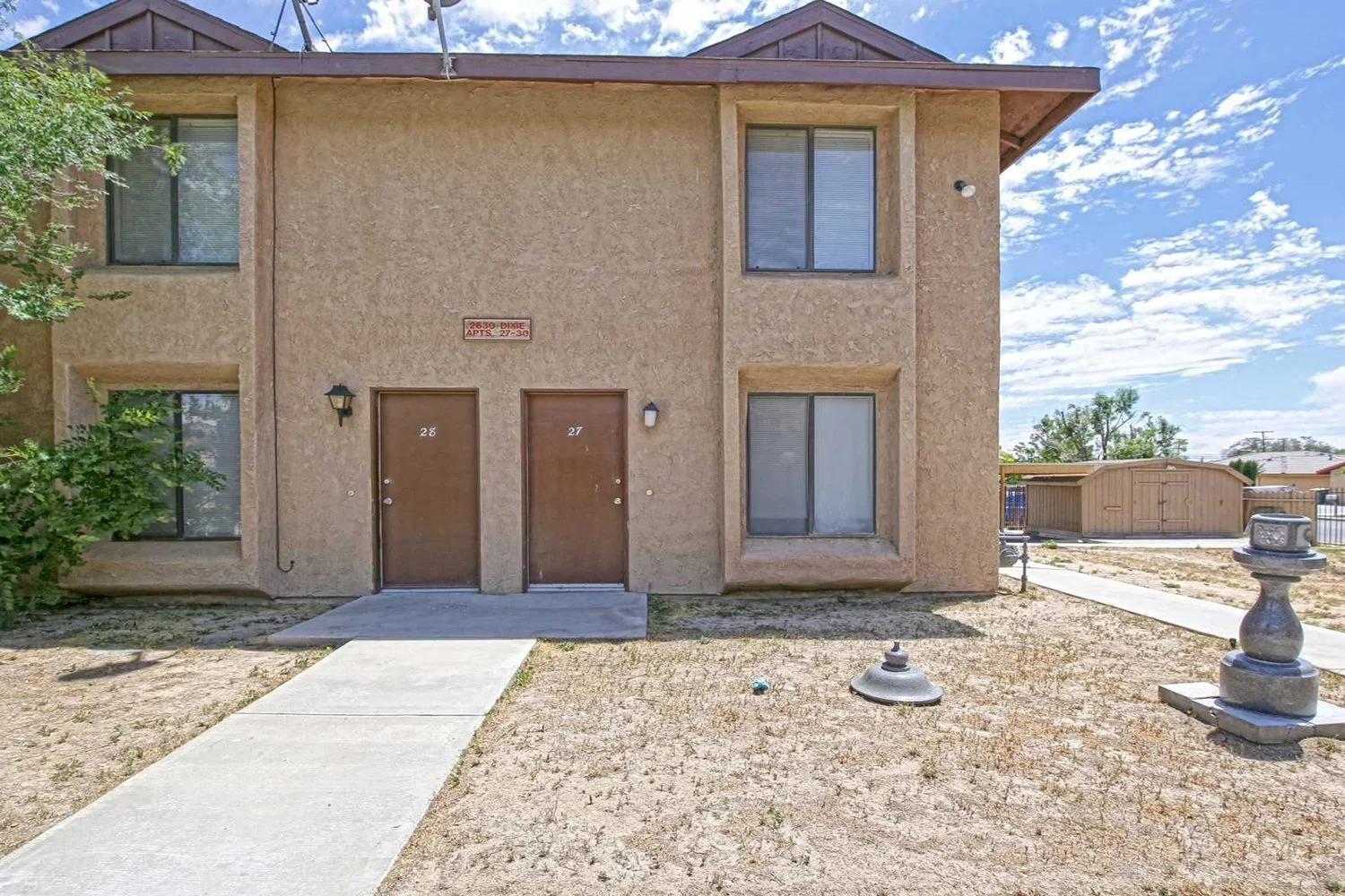 A front view of the building showing a concrete walkway directly to two front doors. 
