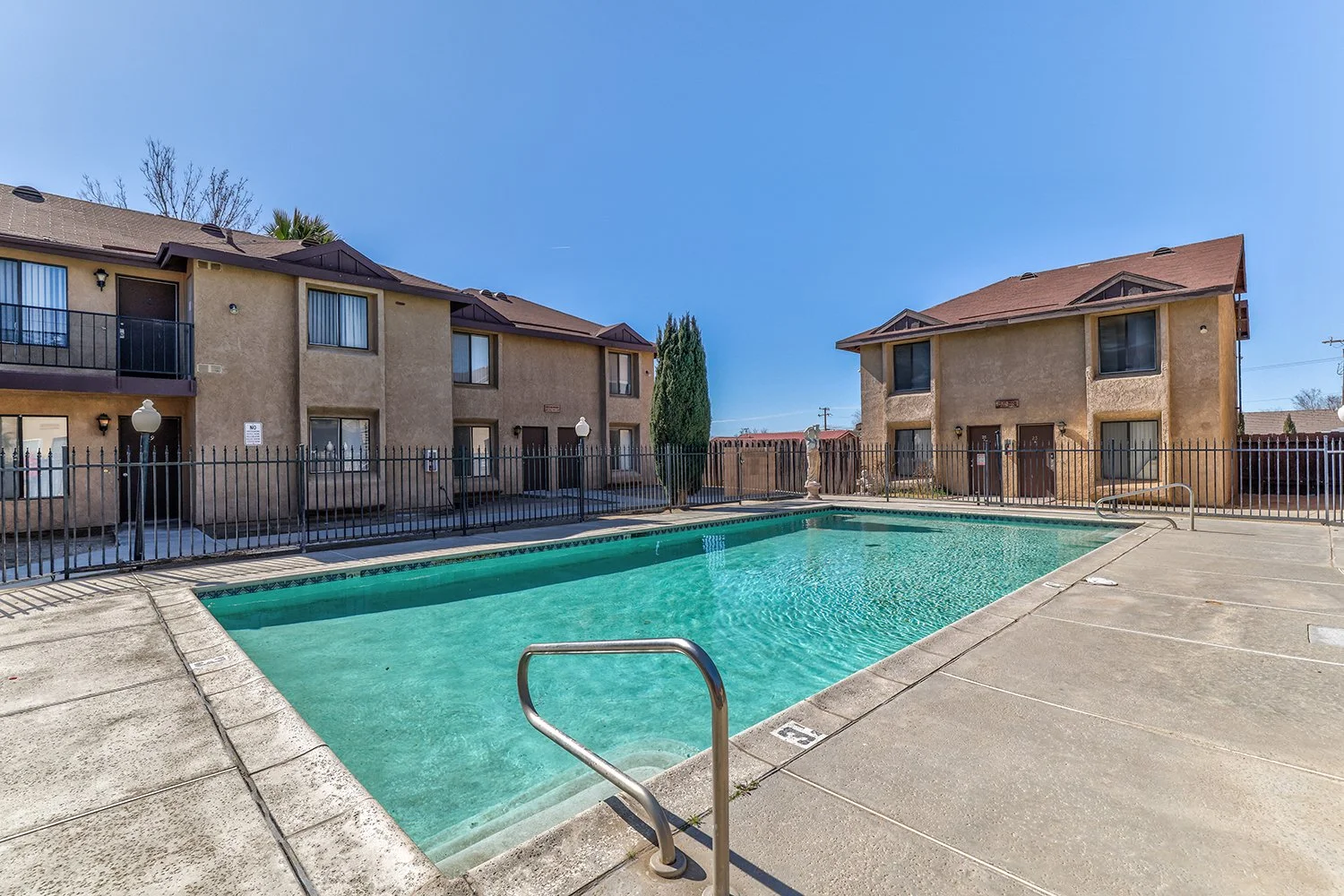 This image showcases a large, shimmering pool enclosed in a safety fence. 