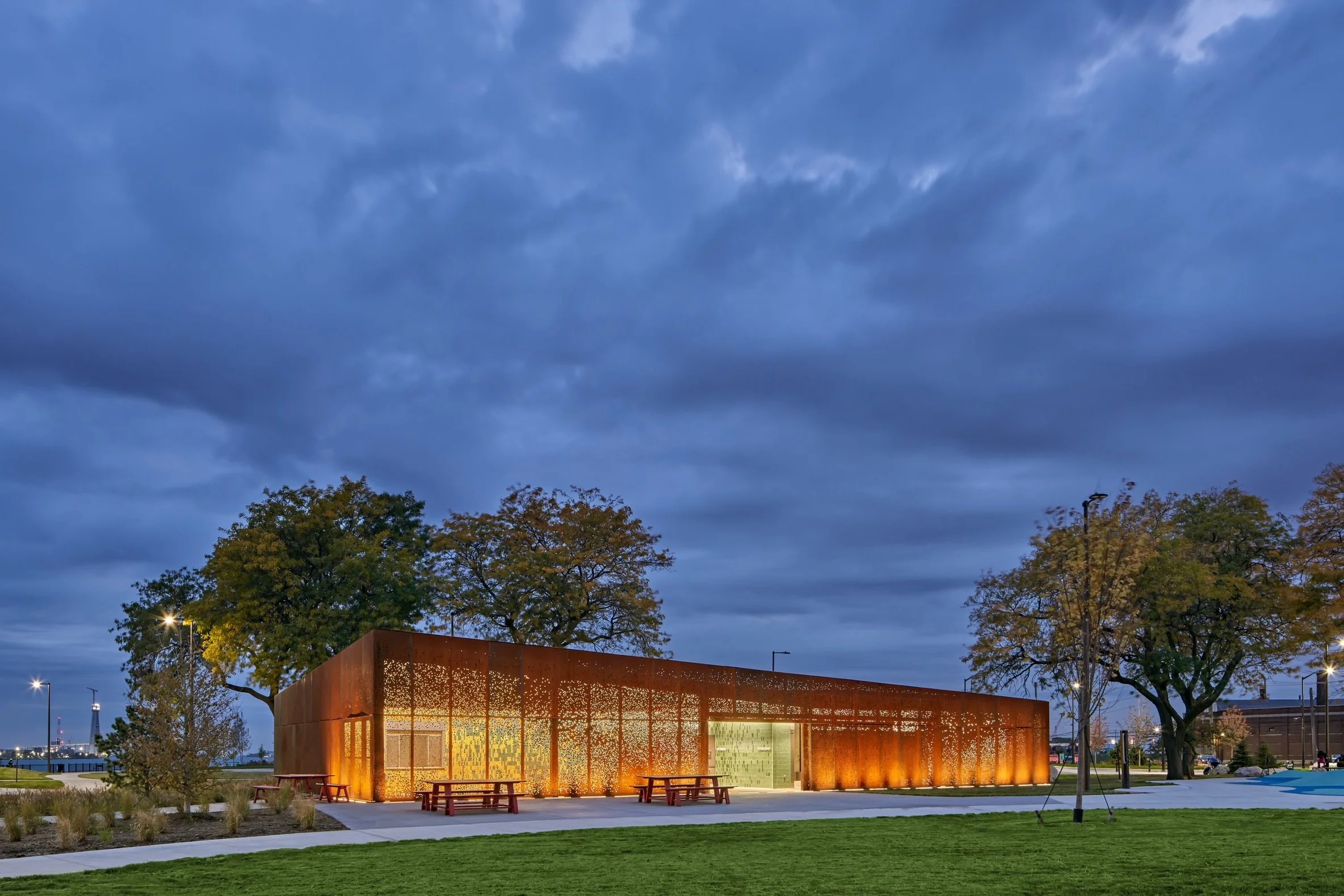 Night shot of the pavilion showing light glowing through perforated facade