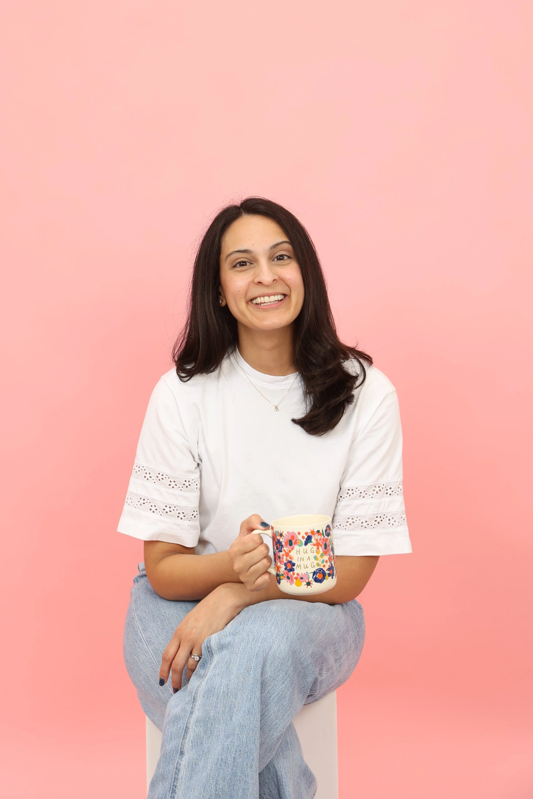 A headshot of Jeanine, a licensed counselor, smiling at the camera and holding a mug of coffee.