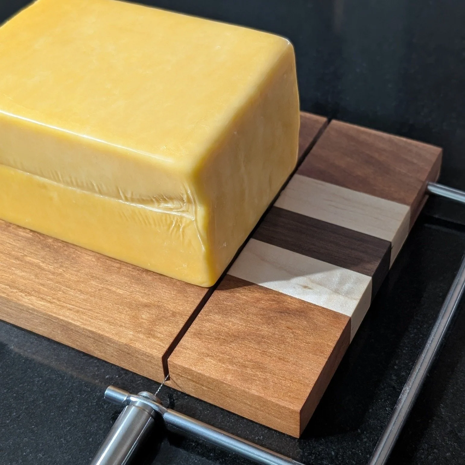 Made of walnut, cherry, and maple, our Cheese Slicer is sure to be a crowd pleaser anytime it&rsquo;s brought out. Easily slice blocks of cheese with the stainless steel handle and wire. Go ahead and grab one as gift while you&rsquo;re at it! This on