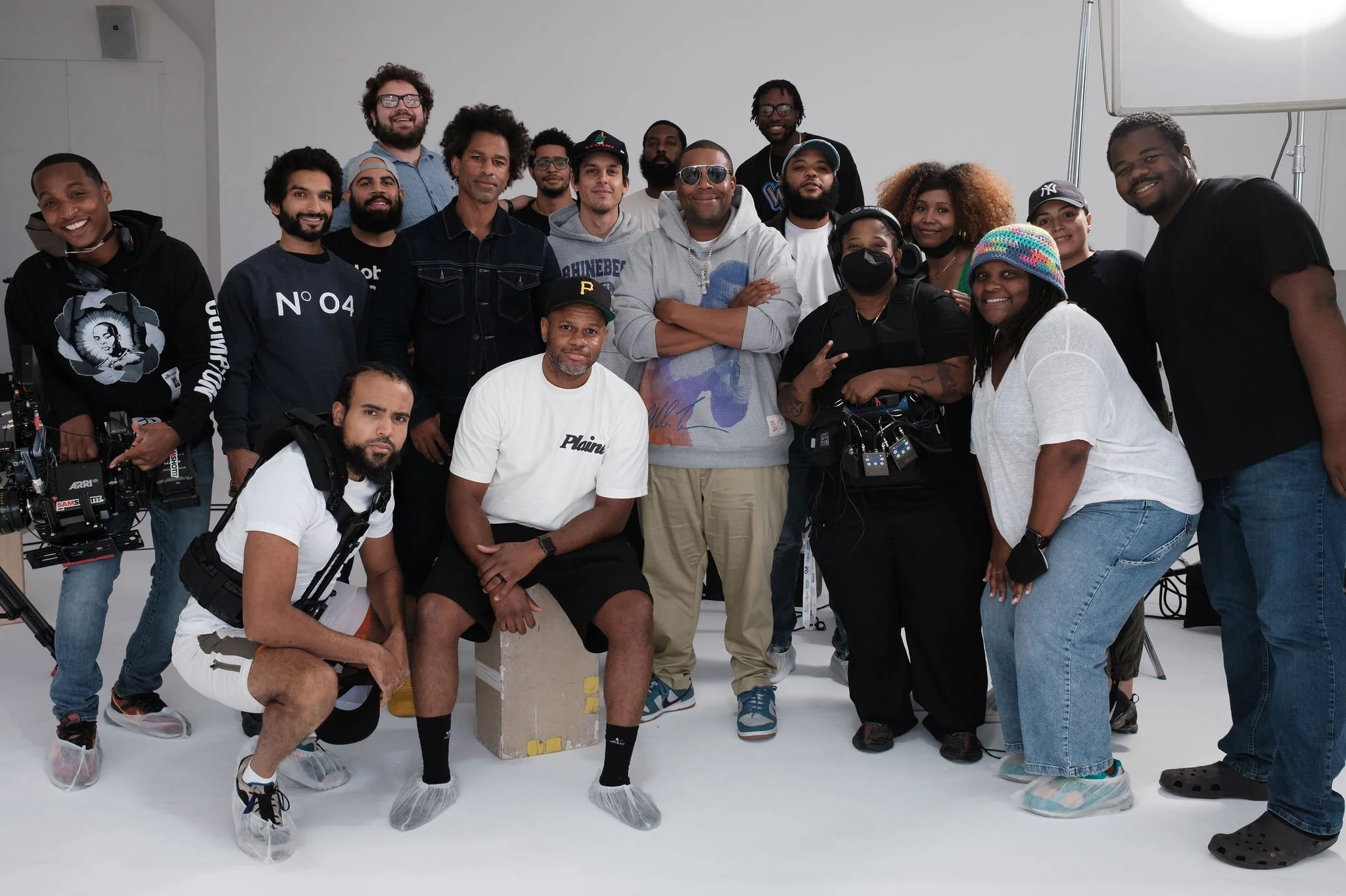 Group of diverse people on a film set, some wearing headsets, with professional equipment, and a white background.