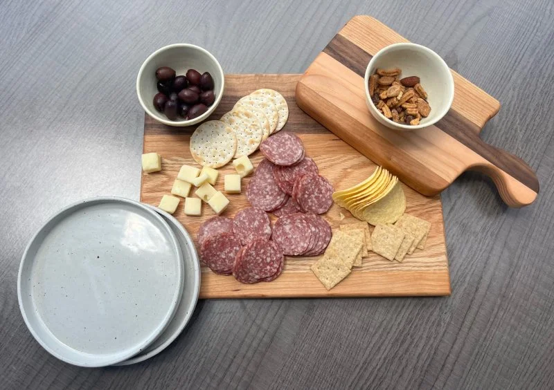 A photo of a hand-made charcuterie board and ceramic bowls with cheese and crackers. Charcuterie boards can be made in the Char-CUTE-rie class at Groundworks Art Lab in Boulder, CO