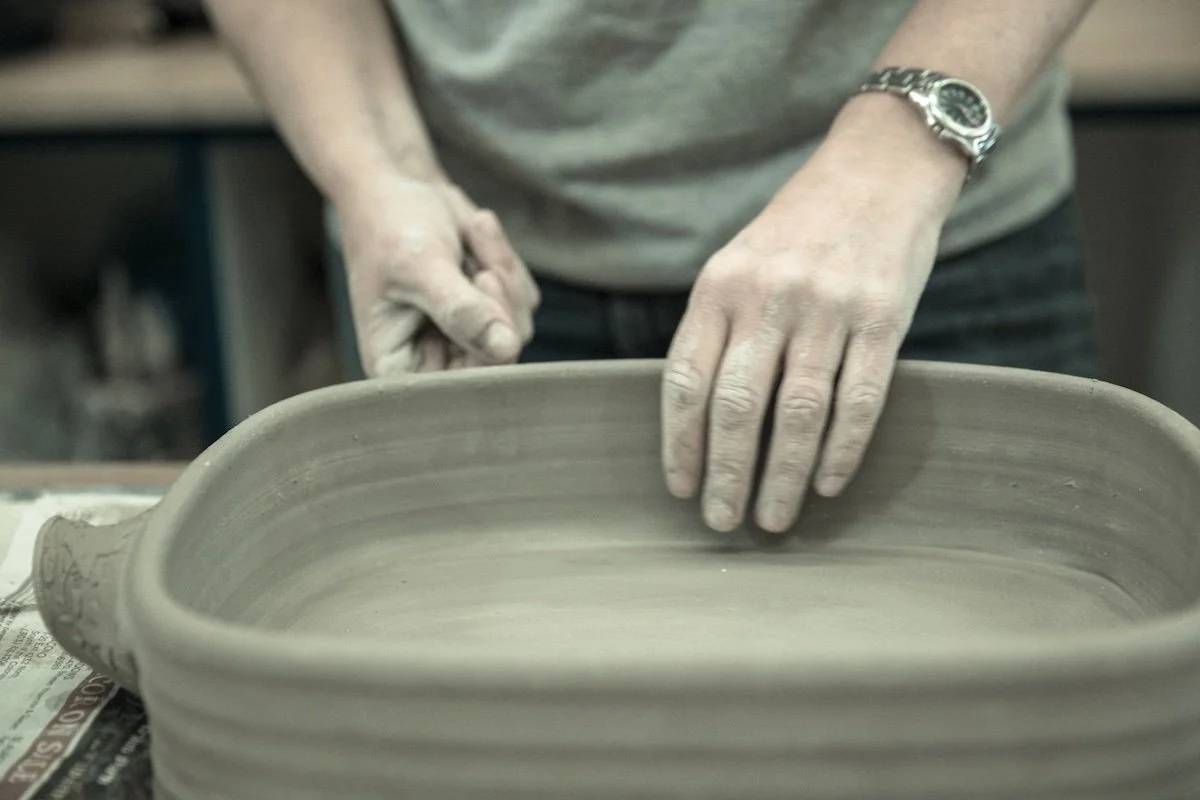 Person hand-building a clay casserole dish at Groundworks Art Lab in Boulder, CO