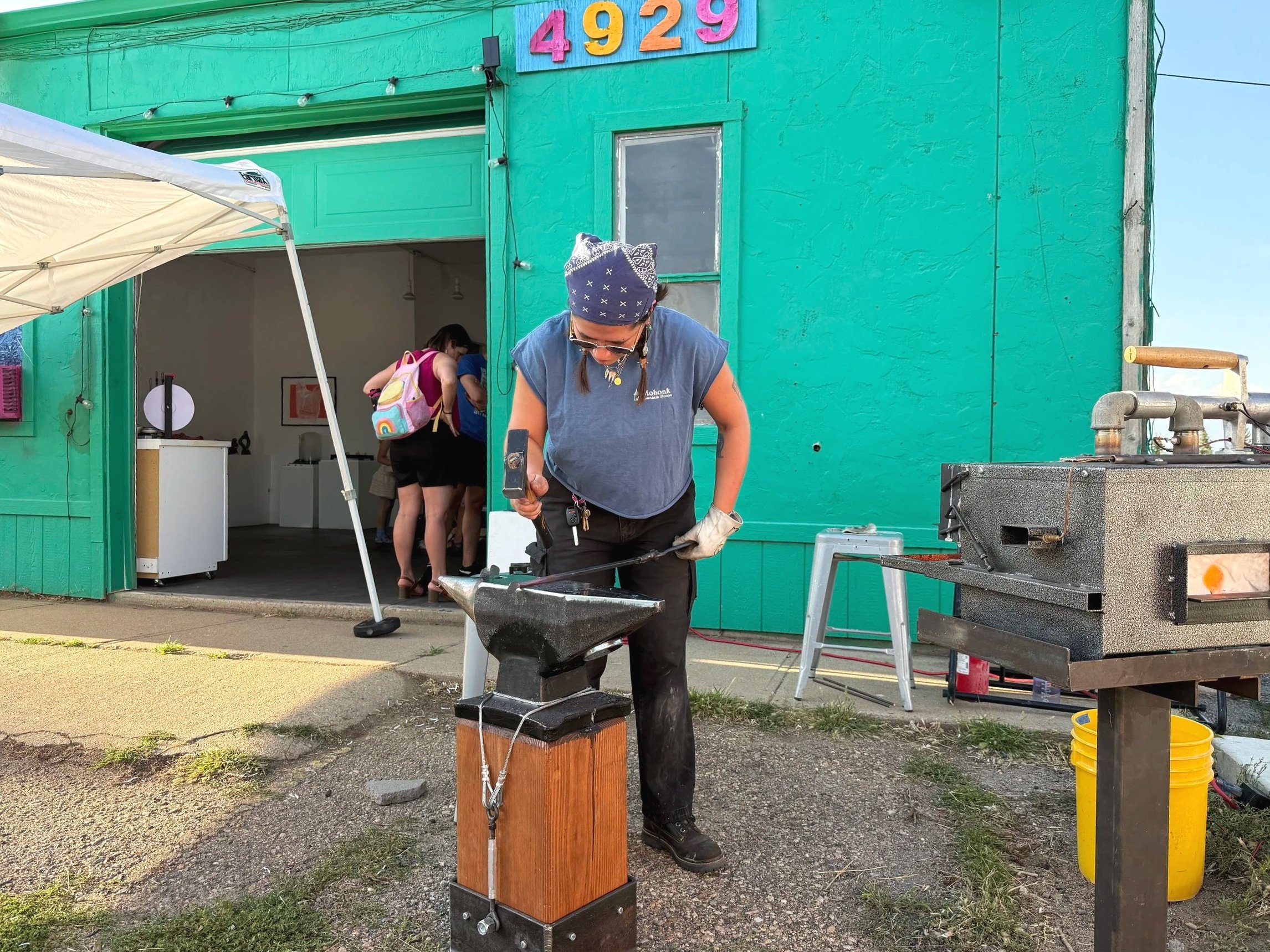 person demonstrates blacksmithing in front of  art center