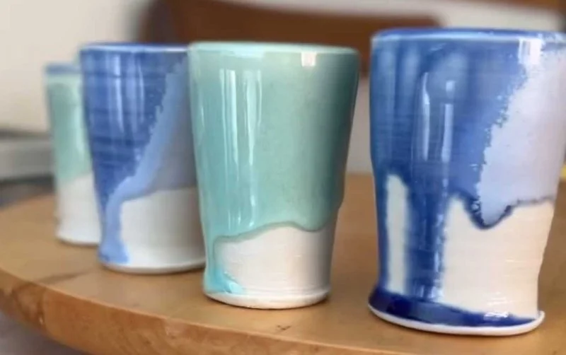 A collection of soda-fired ceramic cups with dripping blue and green glaze made in the Soda Fired Level 2 pottery class at Groundworks Art Lab in Boulder, CO