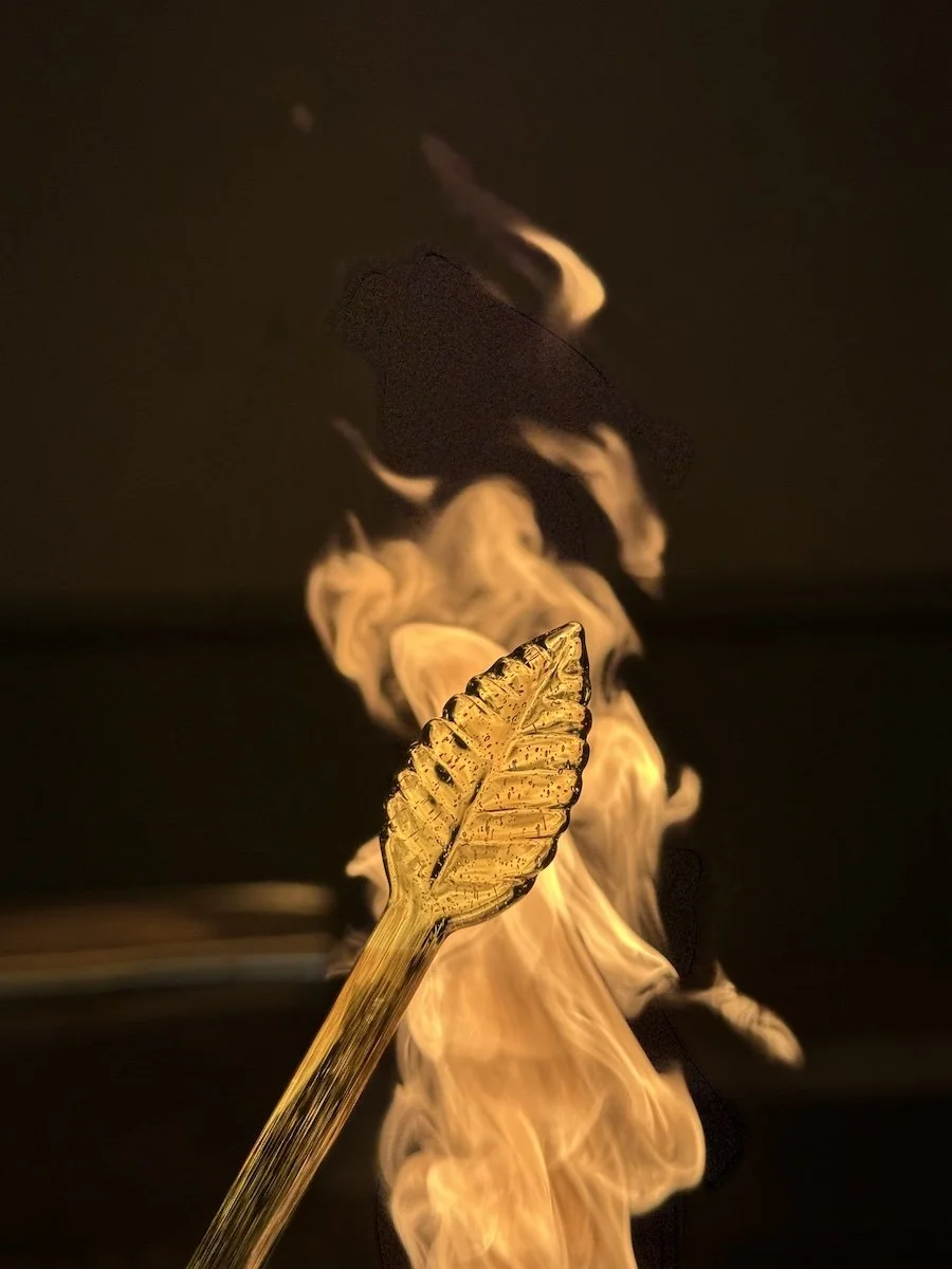 A borosilicate glass tube shaped into a leaf using flameworking. Groundworks Art Lab in Boulder, CO offers flameworking classes in their low-fire glass studio