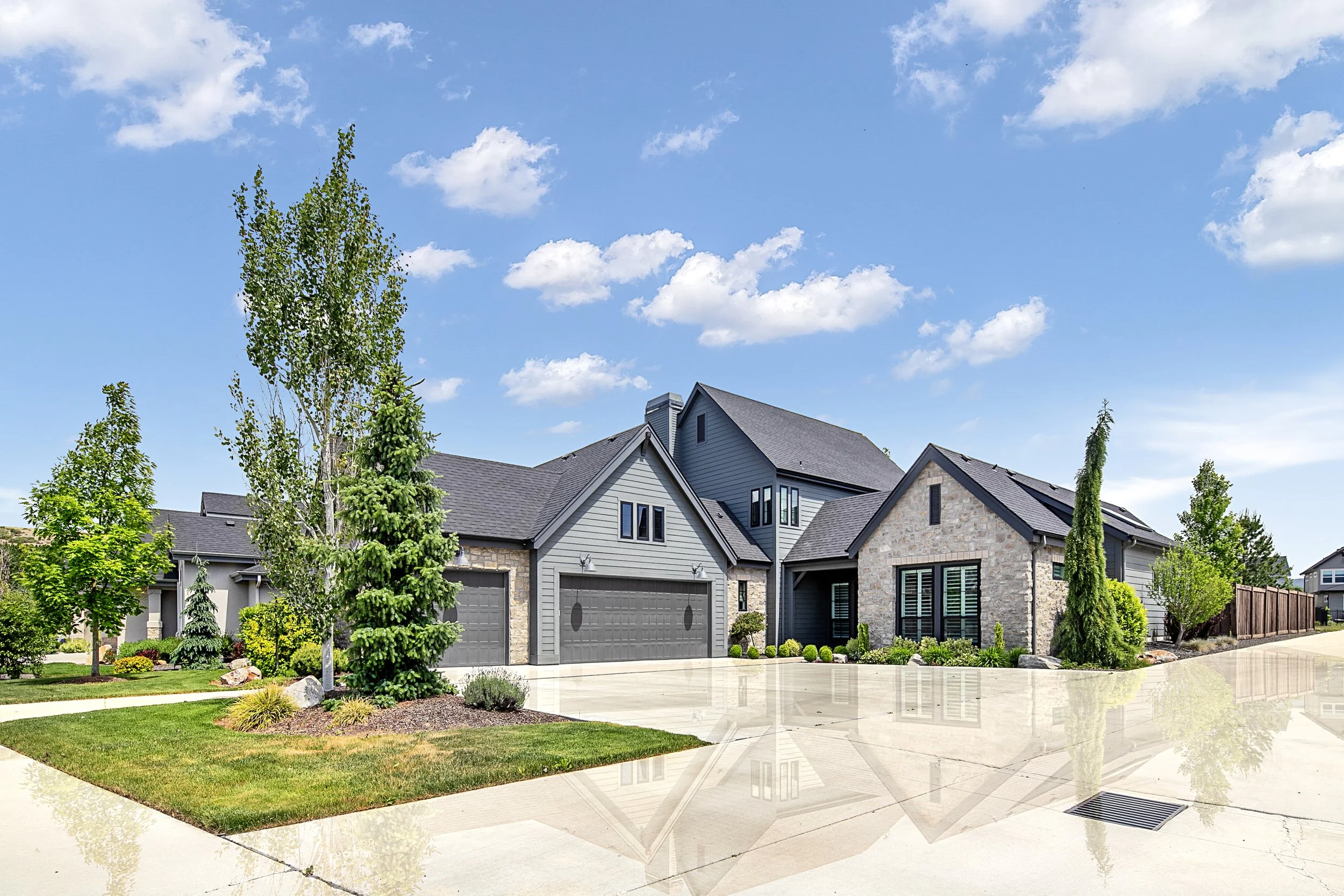 Transitional luxury home in Boise, Idaho blending grey lap siding, natural stone, and black-framed windows