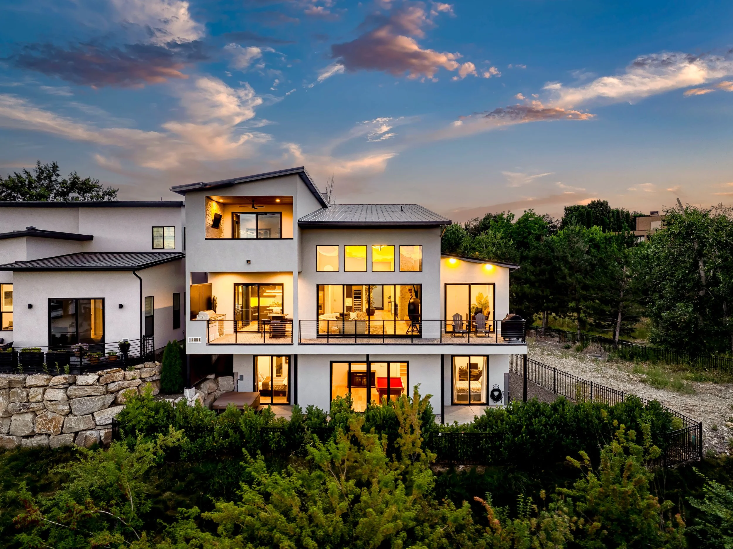 Luxury multi-level home exterior lit up at dusk, set against a landscaped hillside