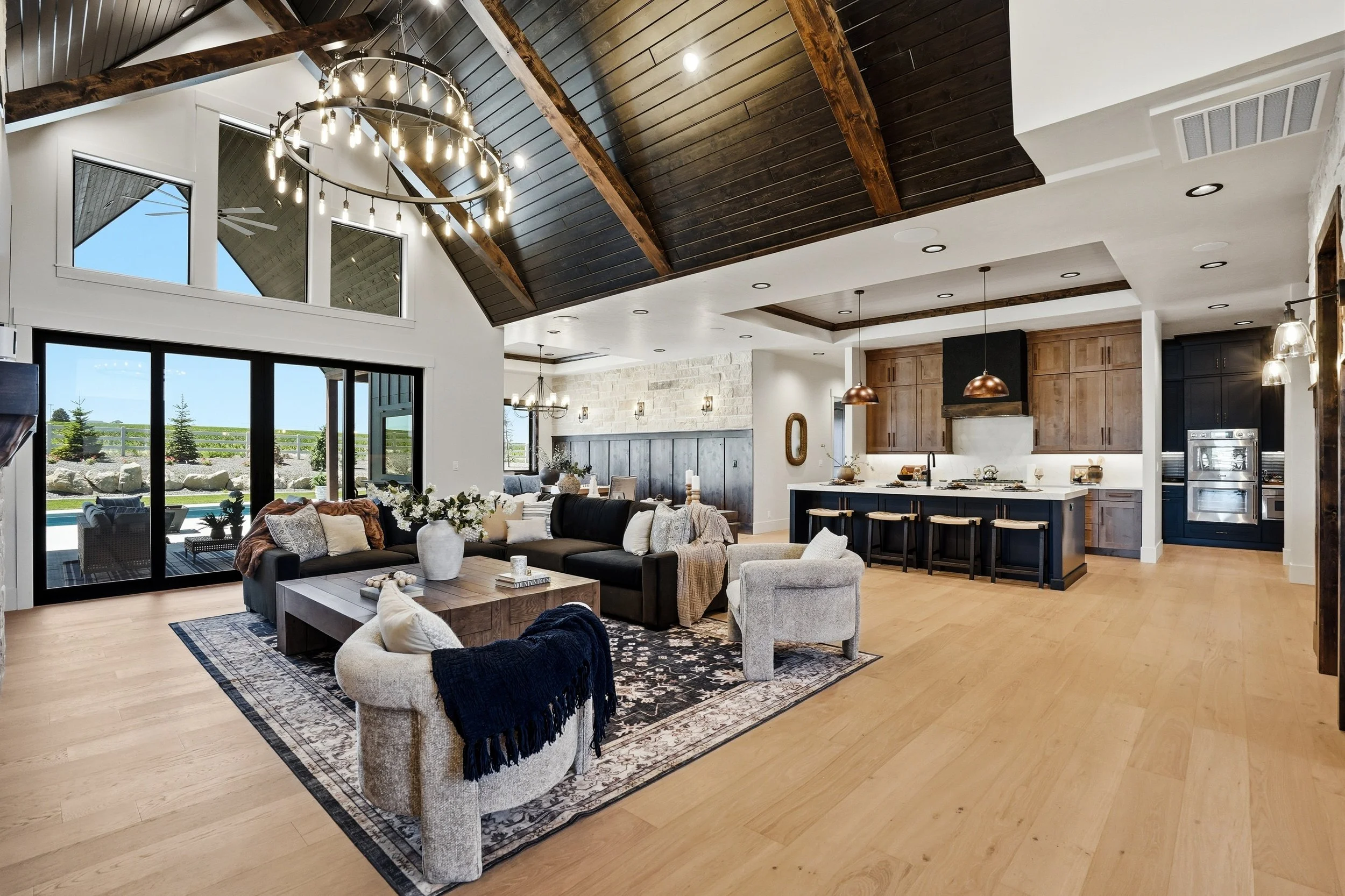 Open-concept great room and chef's kitchen with vaulted wood-beam ceiling and wall of windows in an Eagle, Idaho luxury home