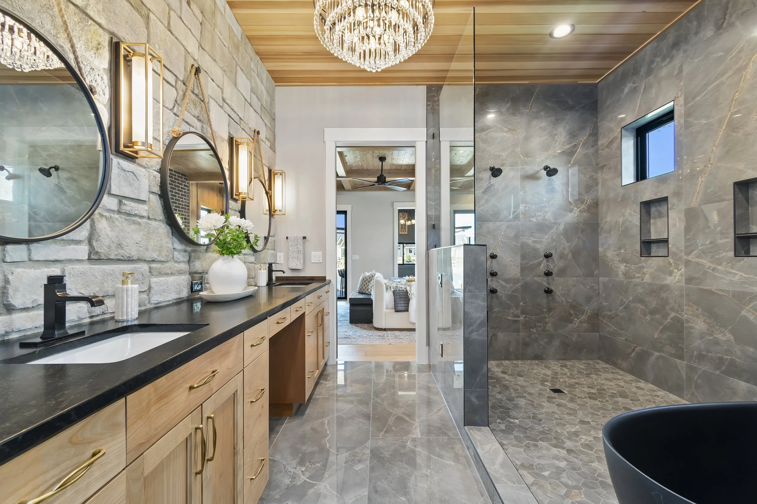 Luxury primary bathroom with double vanity, stone accent wall, freestanding tub, and walk-in tiled shower