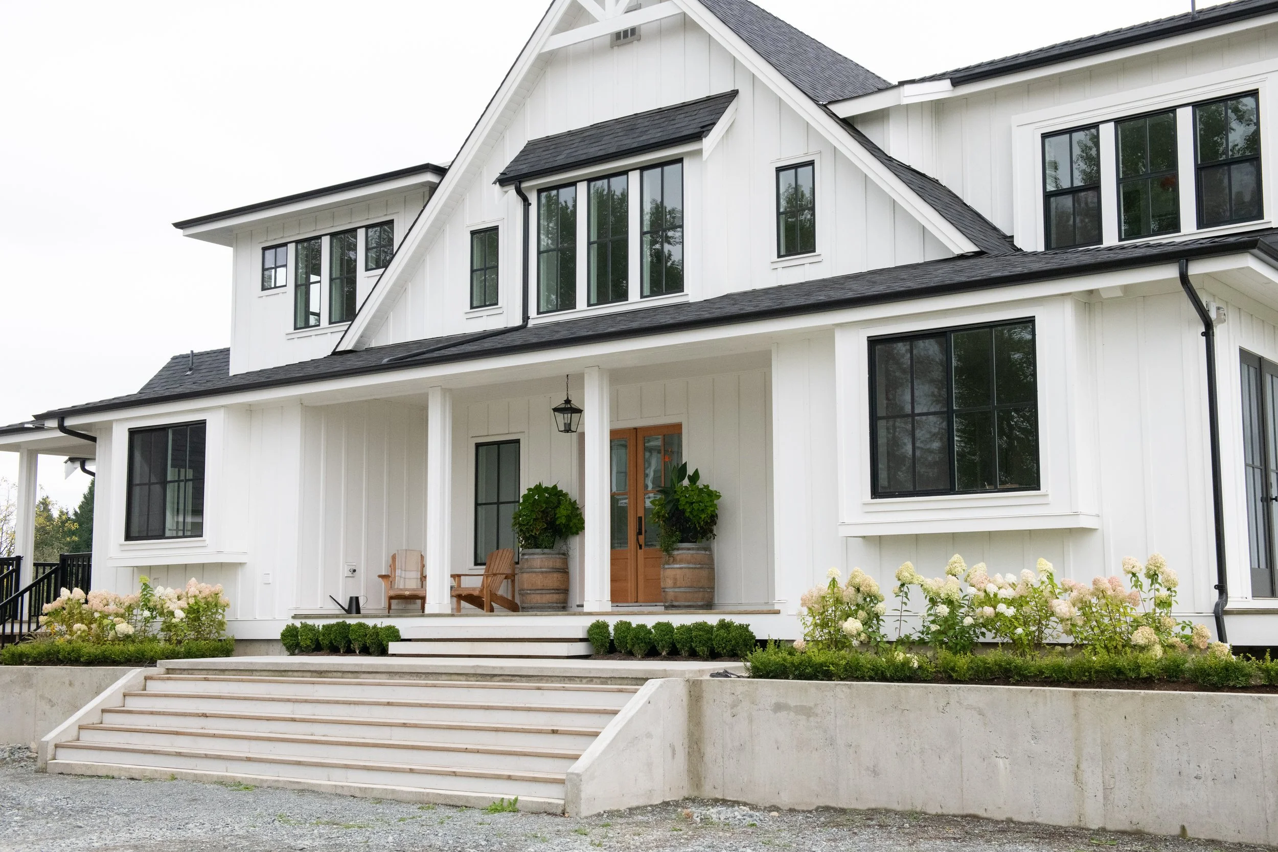 Modern farmhouse luxury home with white board-and-batten siding, black windows, and a covered front porch