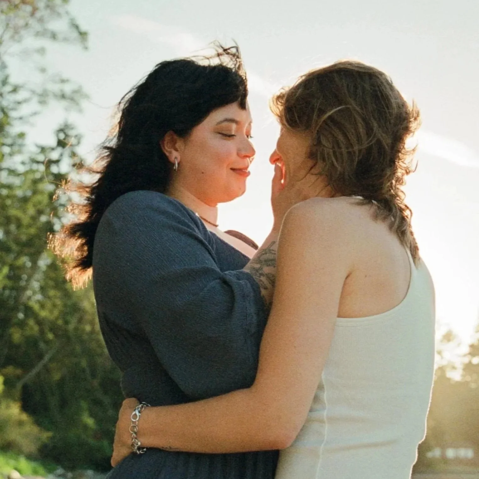 Two women with shoulder-length hair hold each other, gazing lovingly into each other's eyes. Shot by Seattle photographer Holly Stevens.