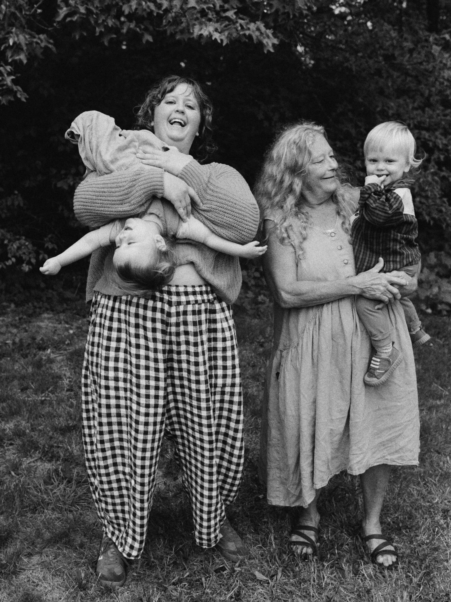 Two women and two children outdoors, with women holding children and smiling. Shot by Seattle-based queer photographer Holly Stevens.