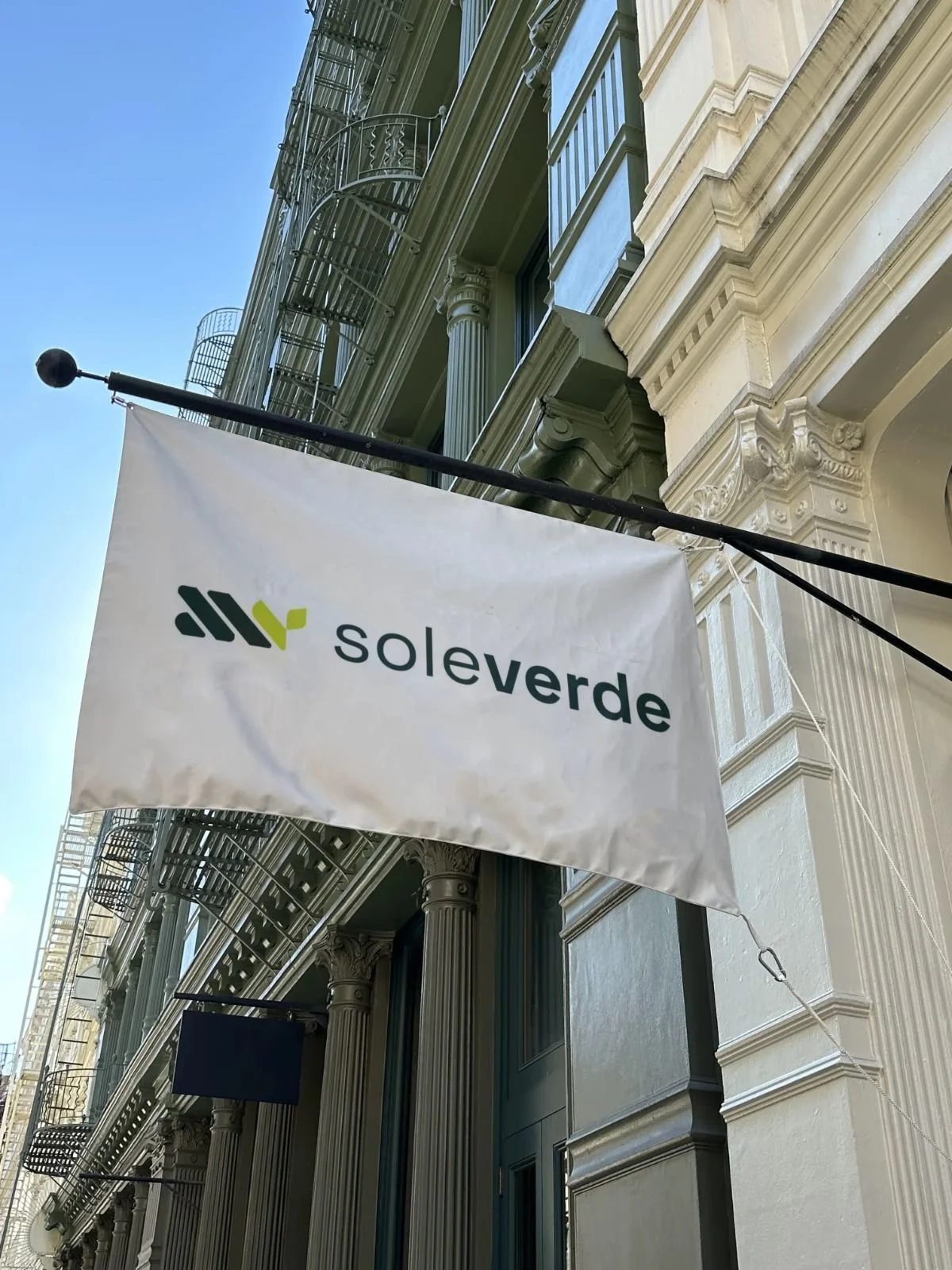 A white flag with the logo and name of Solverde, hanging outside a classic building with tall columns and decorative moldings.