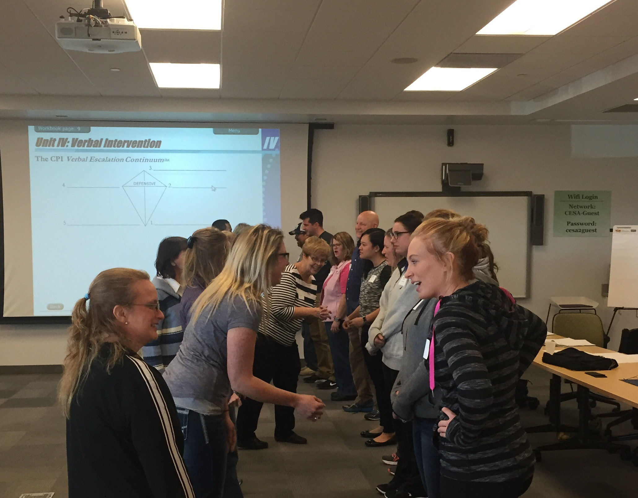 Around 20 people stand in two lines facing each other to practice NVCI techniques