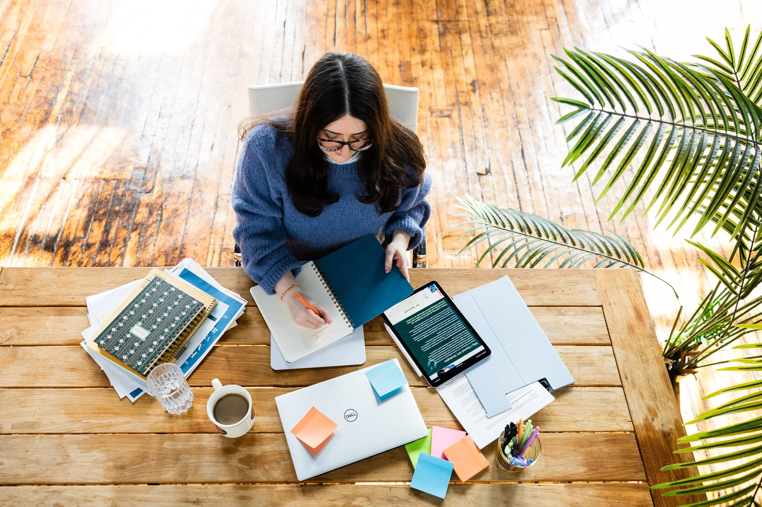 Aline working at her desk with a laptop and notebook