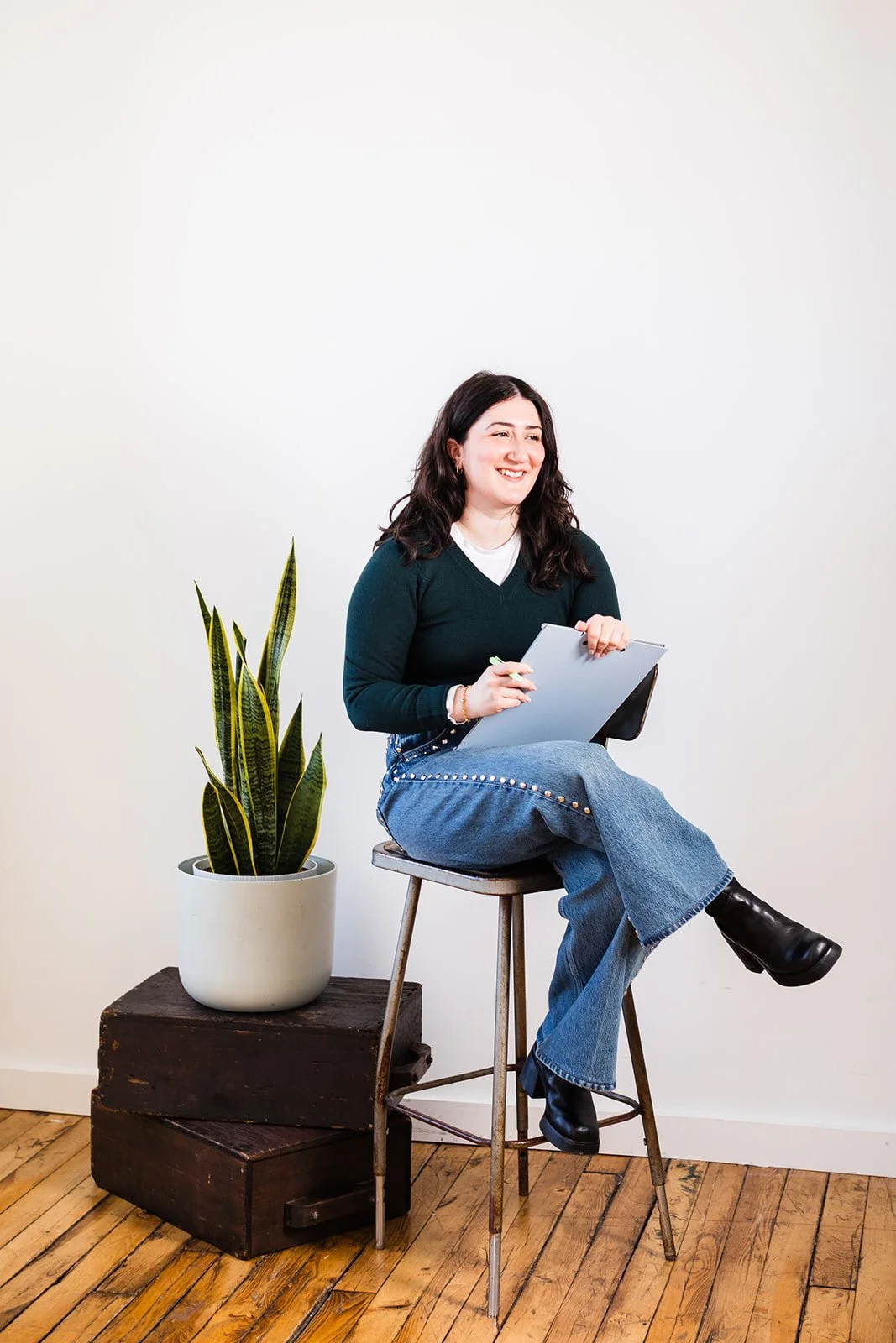 Aline sitting on a high stool while holding a notebook