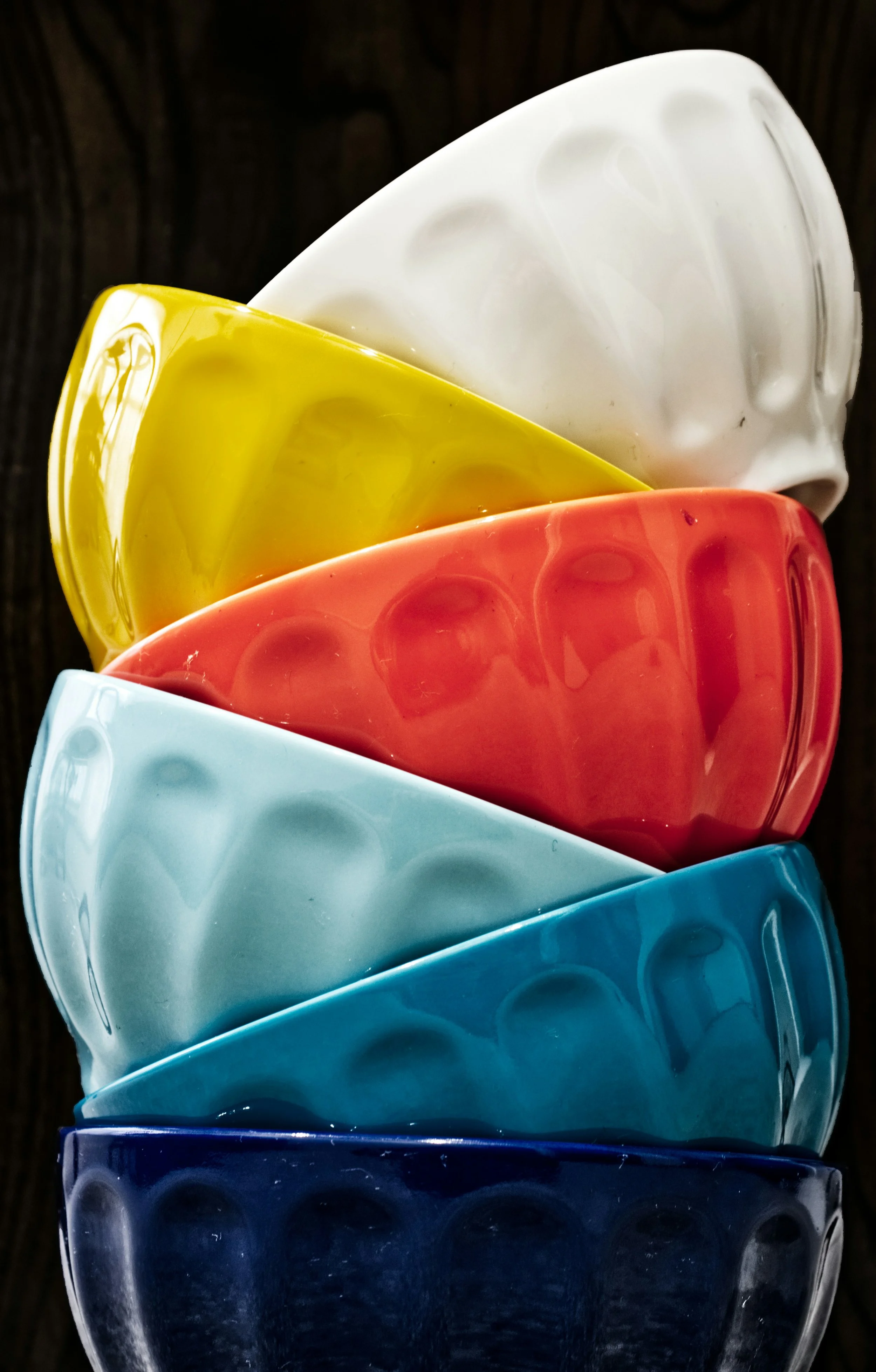 Stack of colorful ceramic bowls in white, yellow, orange, light blue, and dark blue.