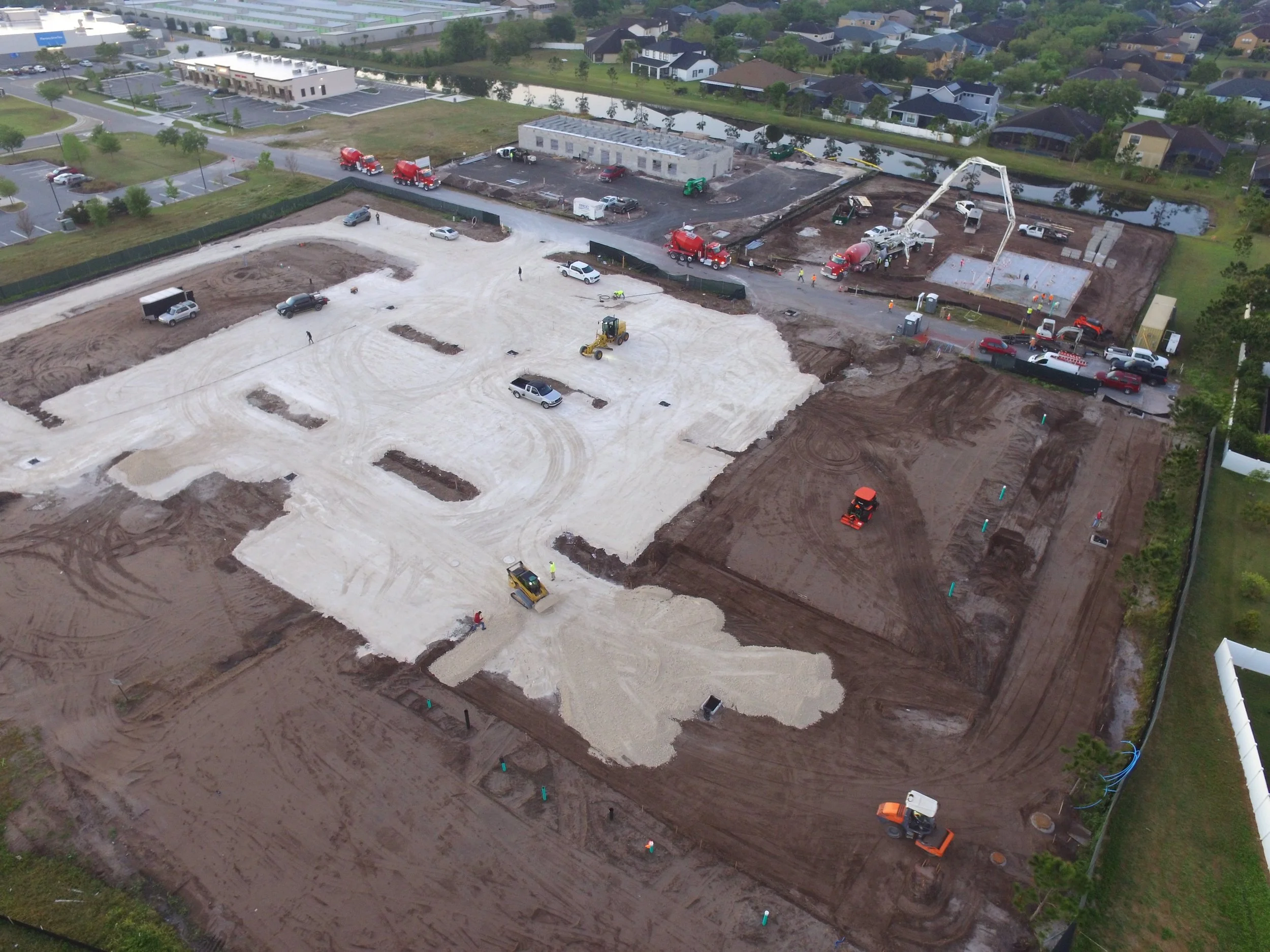 Aerial view of a construction site with heavy machinery and partially constructed foundations.