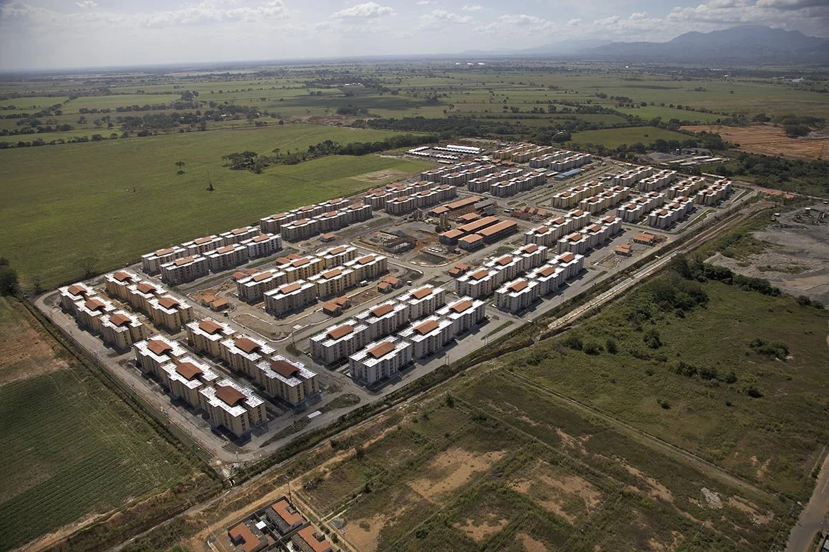 Aerial view of a large residential apartment complex surrounded by green fields and countryside.