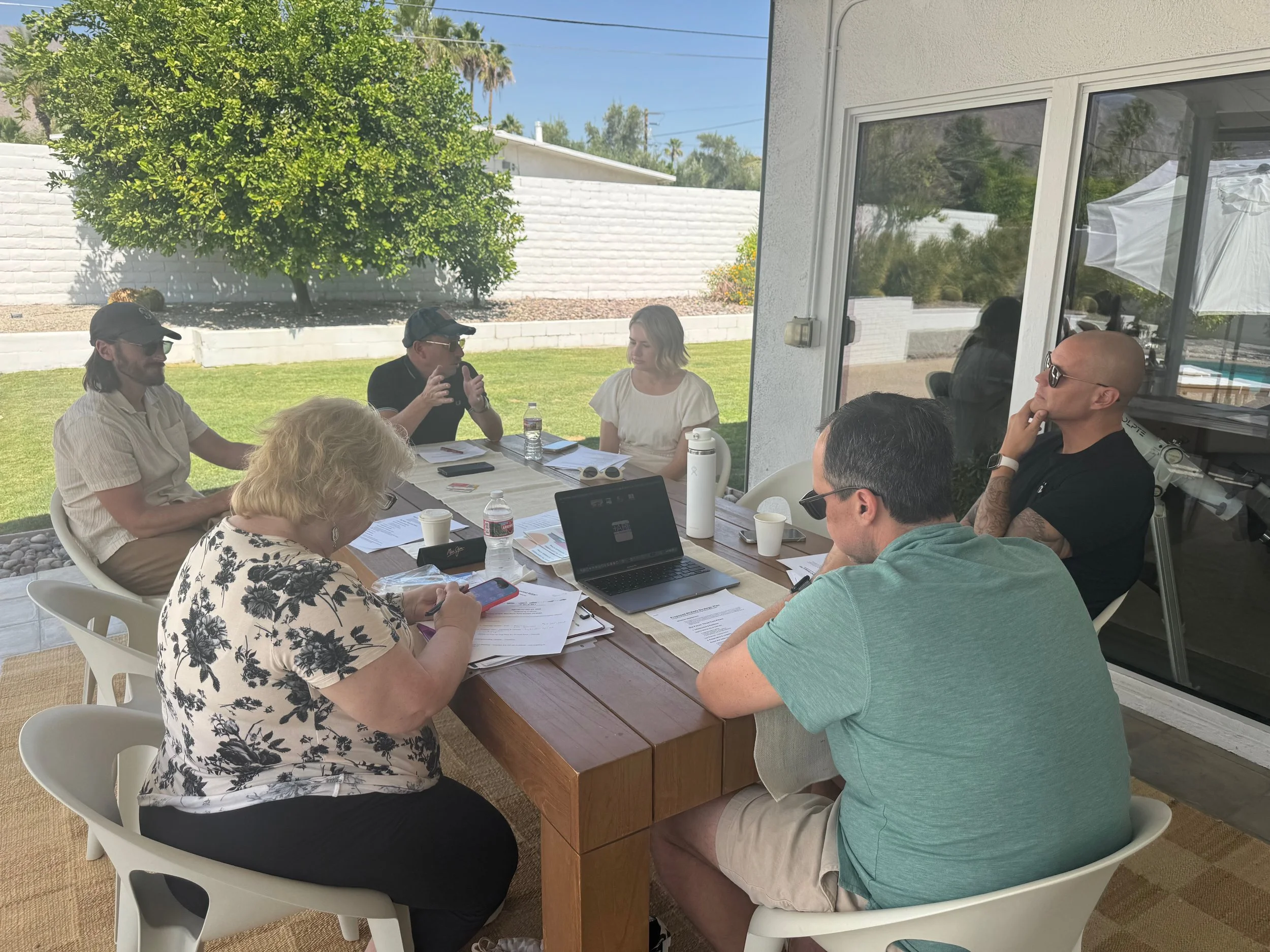 Group of RCENO board members sitting around a table in the backyard