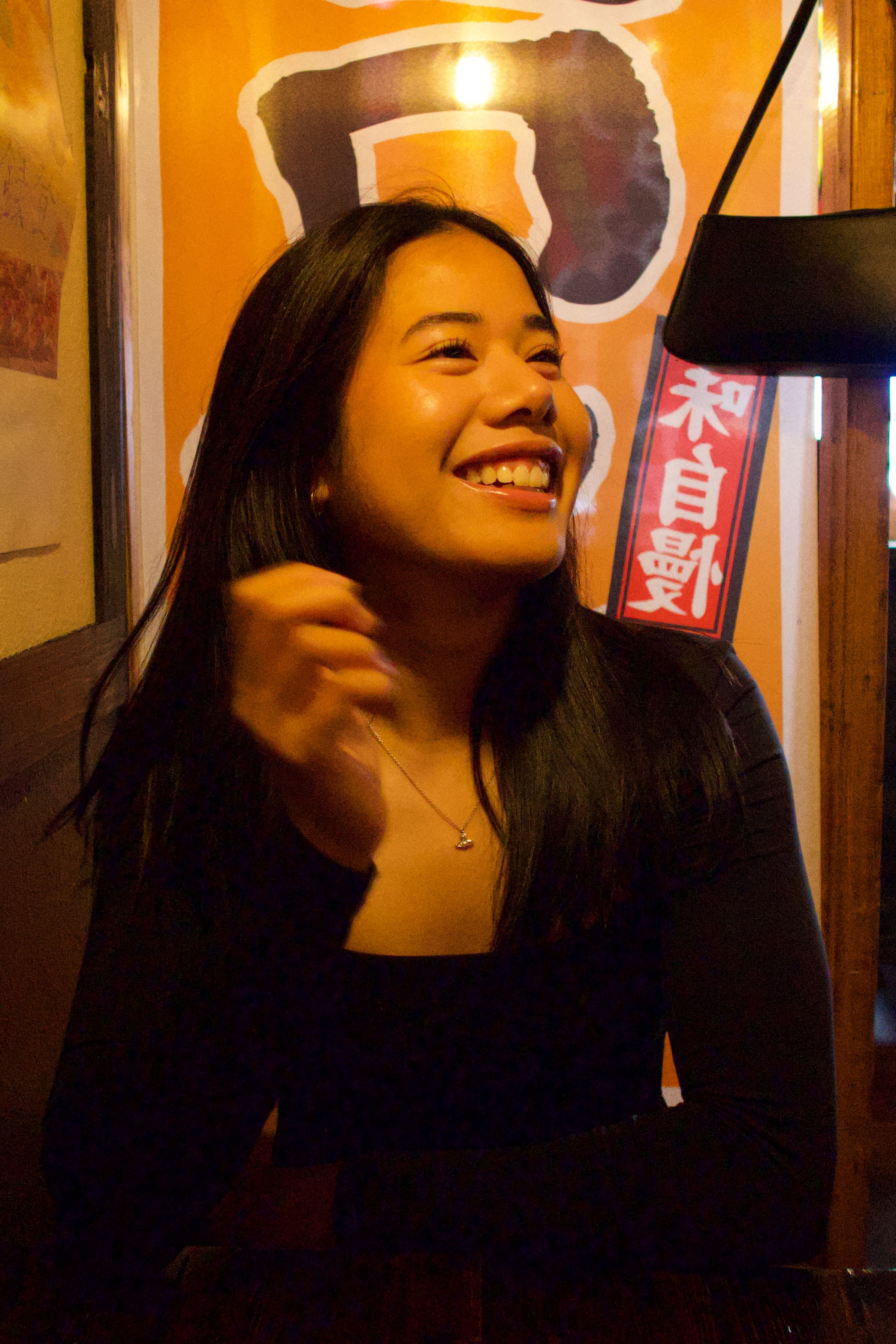 Woman sitting in a restaurant smiling under warm lighting