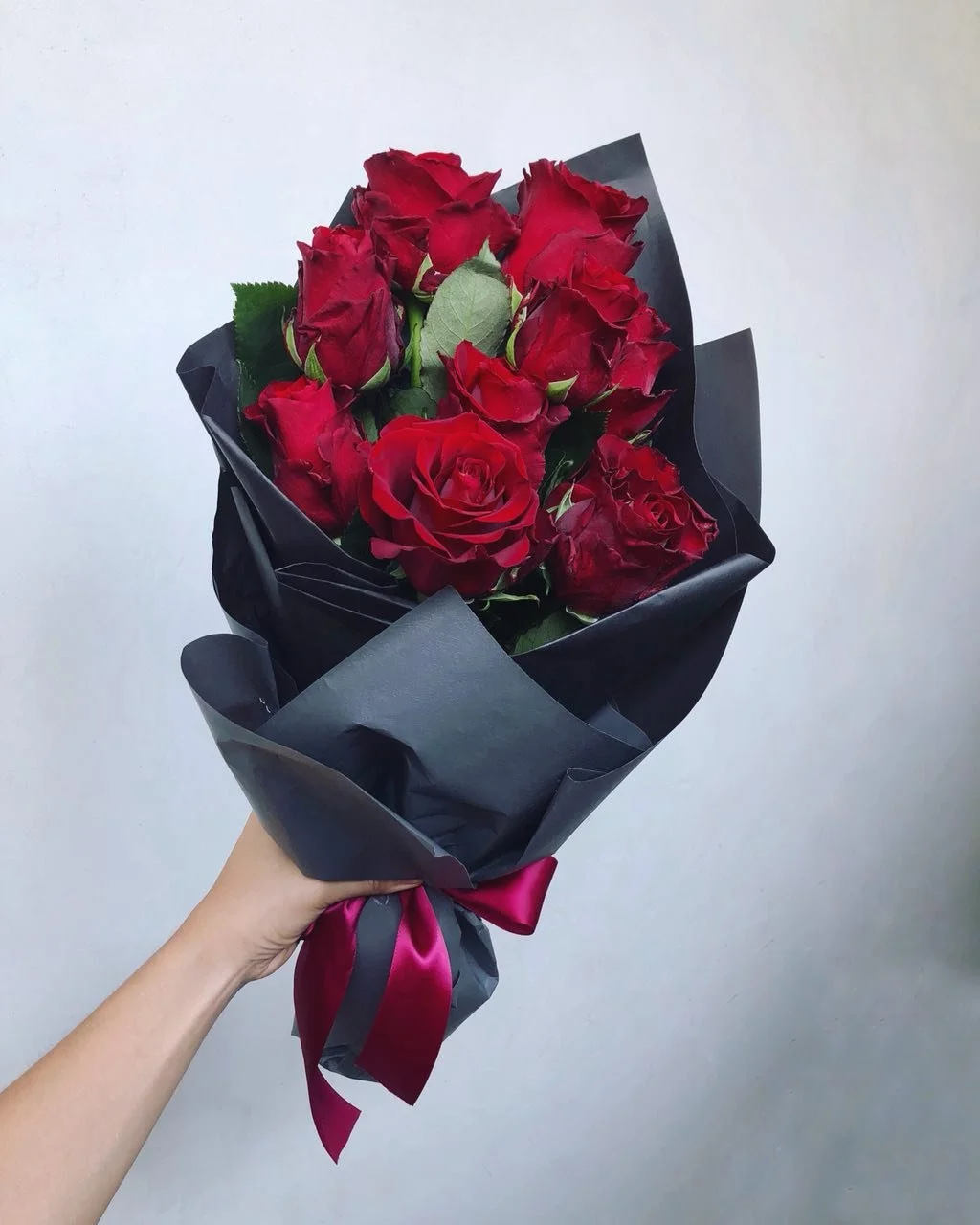A luxurious arrangement of fresh red roses in modern black wrapping, representing the classic standard among different types of flowers for Valentine's Day.