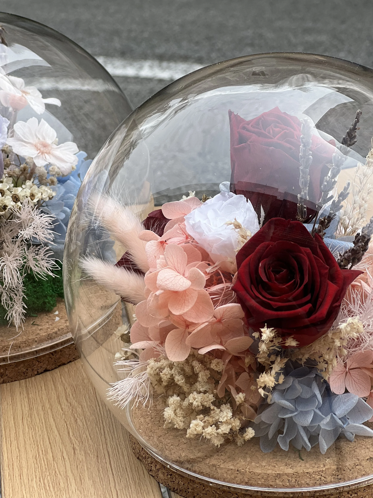 Preserved red roses and pastel pink hydrangea arrangement inside a clear glass dome